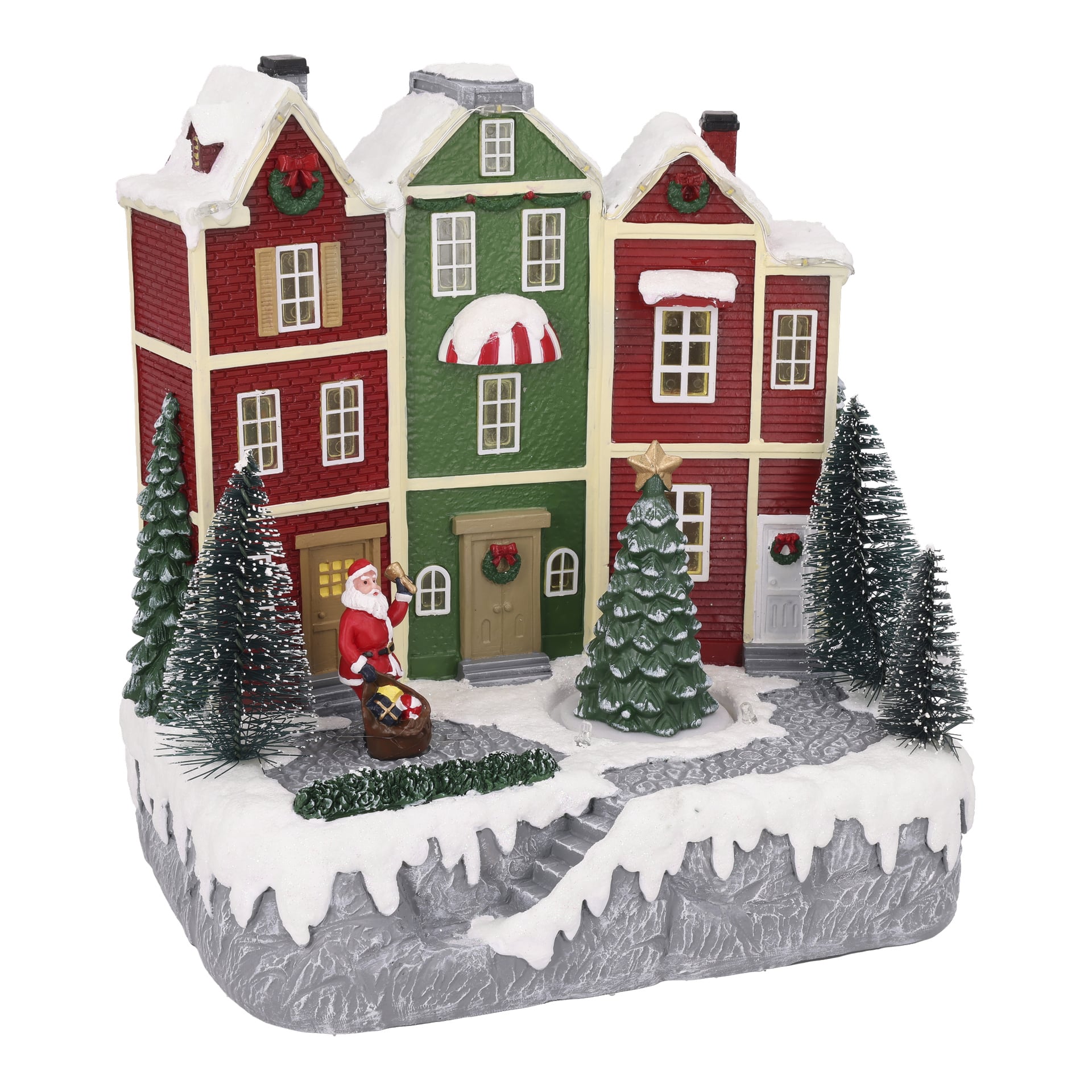 Mini vinterby med tre snötäckta hus, julgran, tallar och jultomten som håller en presentpåse bredvid en trumma.