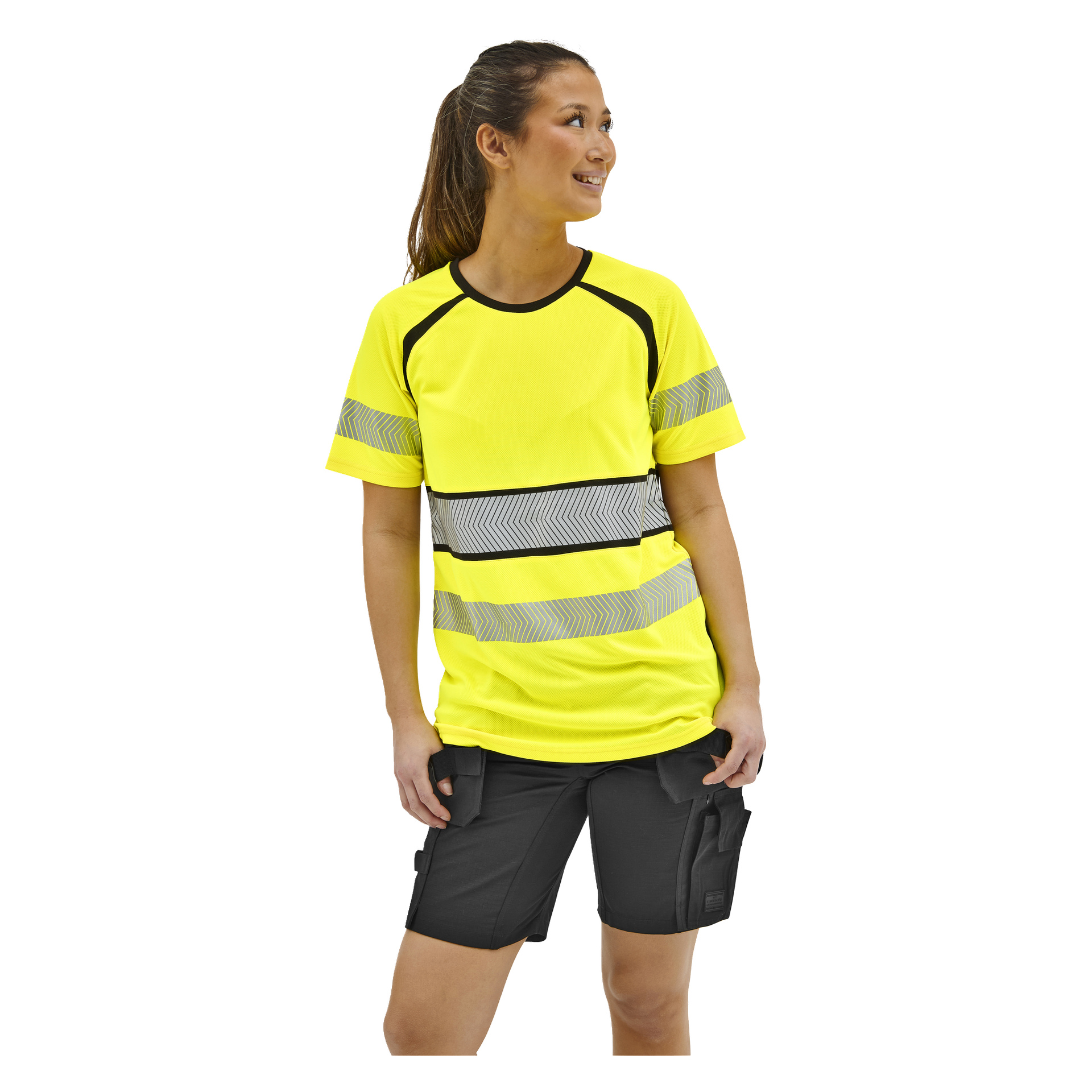 Eine lächelnde Frau in einem gelben, sichtbaren kurzärmeligen Hemd mit reflektierenden Streifen und schwarzen Arbeitsshorts steht auf und schaut zur Seite.