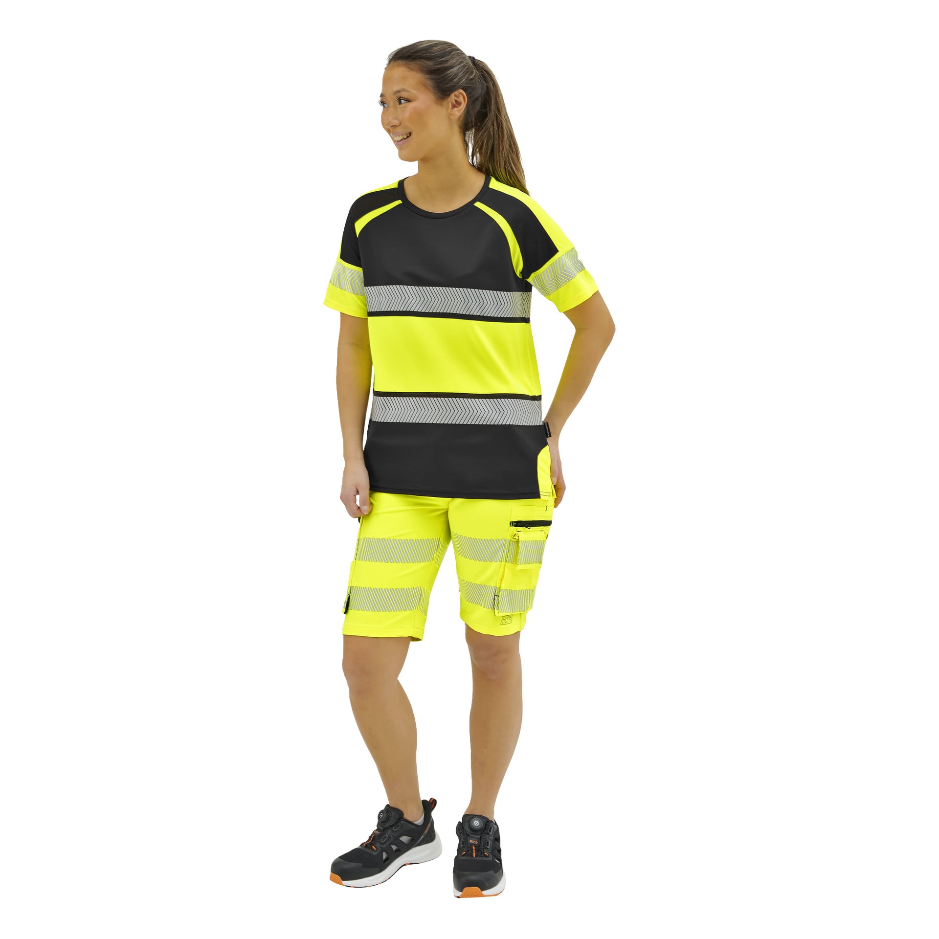En person som bär en gul och svart högsynlig kortärmad tröja och shorts med reflekterande ränder, samt svartgrå sneakers.