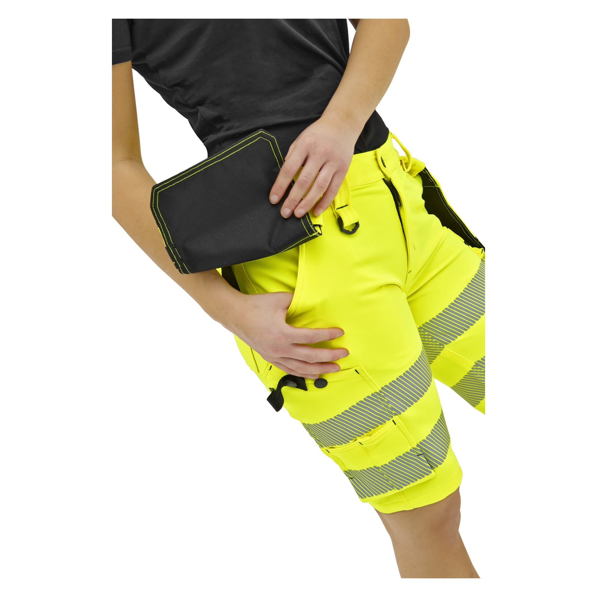 En person i klargula arbetsshorts med reflekterande ränder och svart skjorta håller en svart påse vid höft, bål och lår synliga.