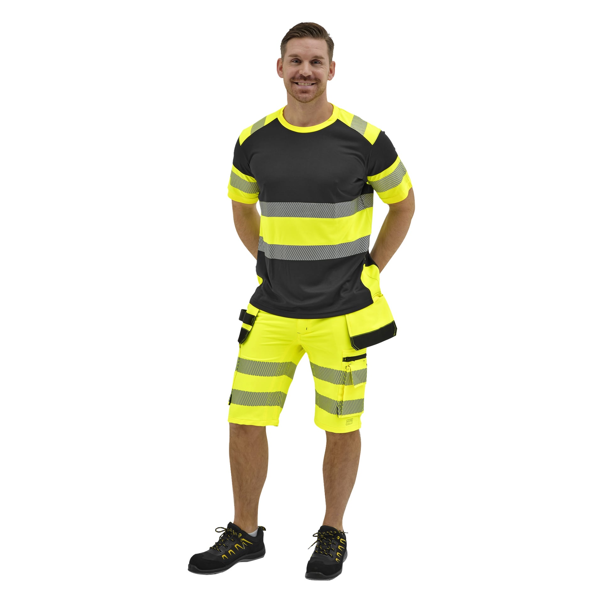 En leende man bär en svart och neongul högsynlig t-shirt och shorts med reflekterande ränder, samt svarta sportskor.