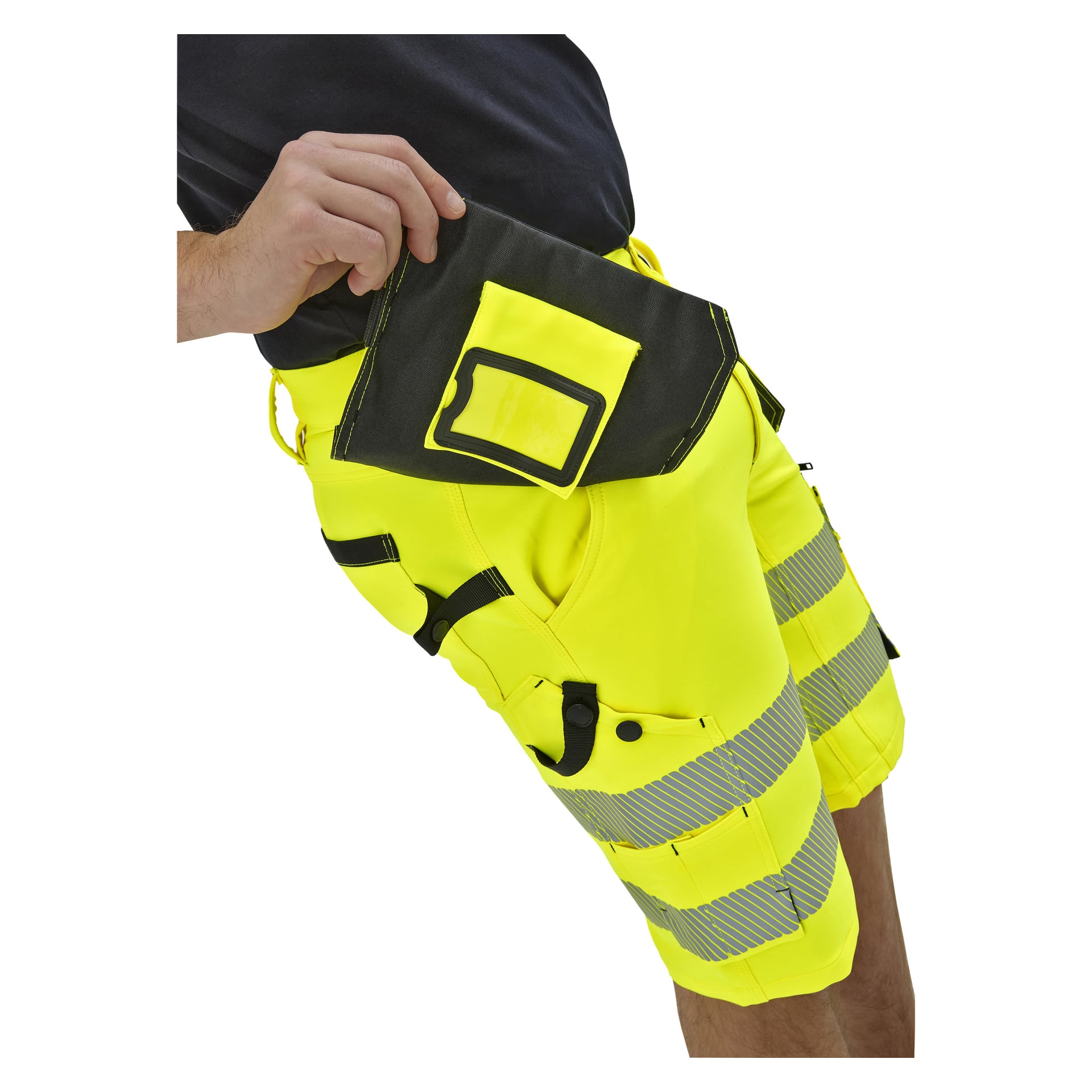 Personen visas från midjan och ner i klargula hög-vis-shorts med reflekterande ränder, hållande en svart och gul påse på shortsen.
