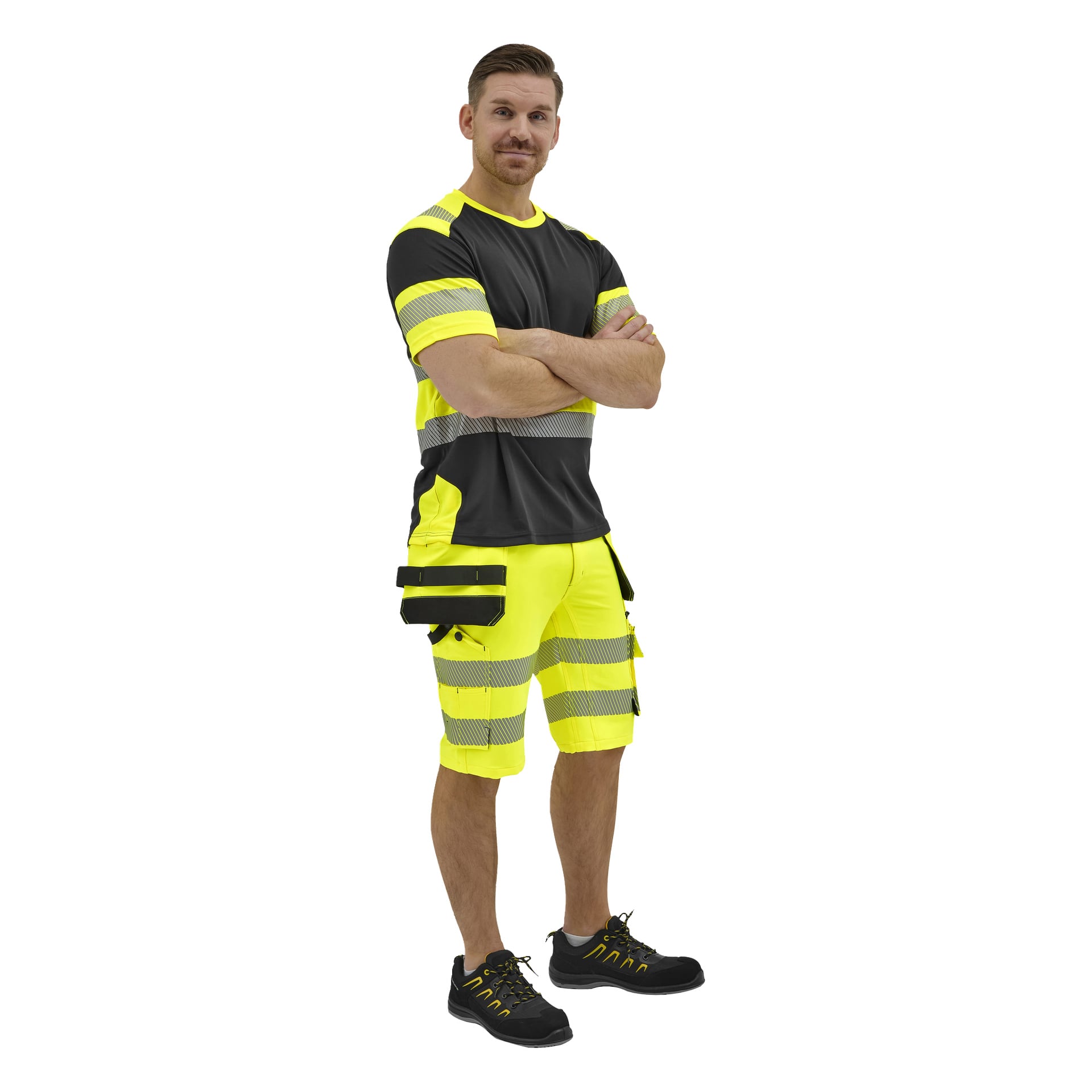 En man står med armarna i kors, klädd i en svart och neongul hög-vis-outfit med reflekterande ränder, gula snörskor och shorts med verktygsfickor.