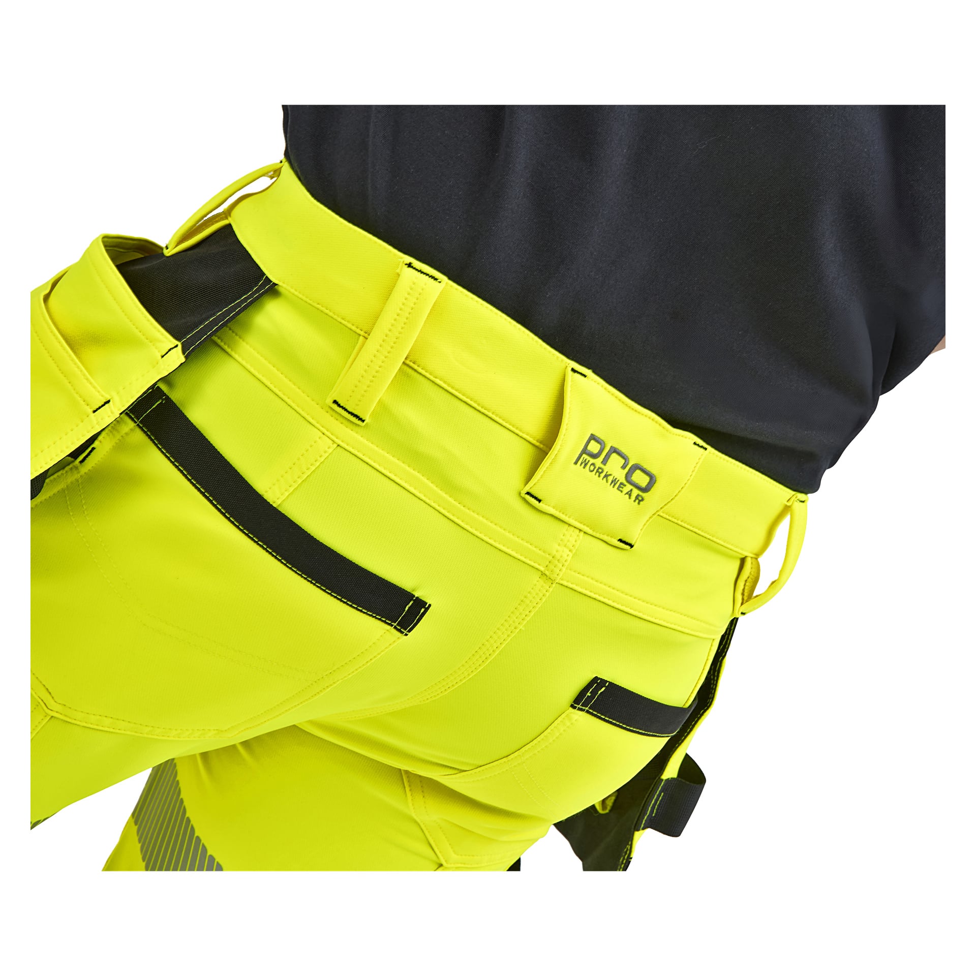 Någon klädd i gula arbetsbyxor med svarta detaljer och verktygsfickor, ihopspelad med en svart skjorta. "PRO Workwear" står på midjebandet.