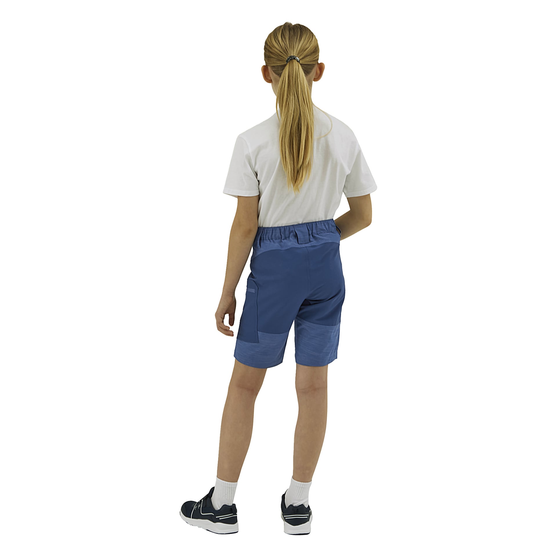 En person med en lång blond hästsvans står med ryggen mot ryggen, klädd i en vit t-shirt, blå shorts, vita strumpor och svarta sneakers.