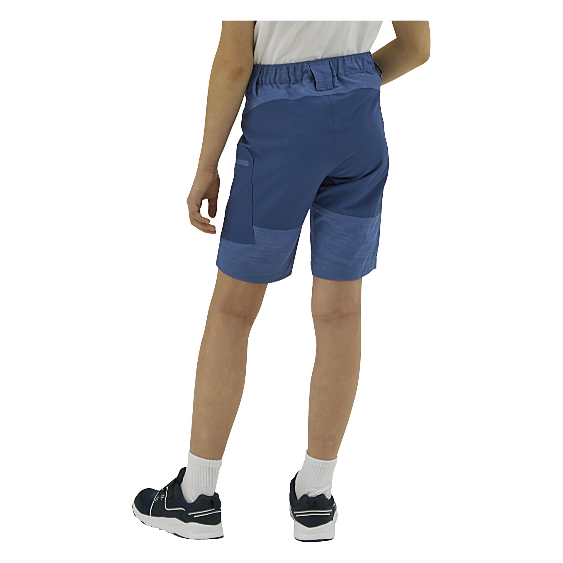 En person i vit skjorta, blå shorts, vita strumpor och svarta sneakers står med ryggen mot betraktaren.