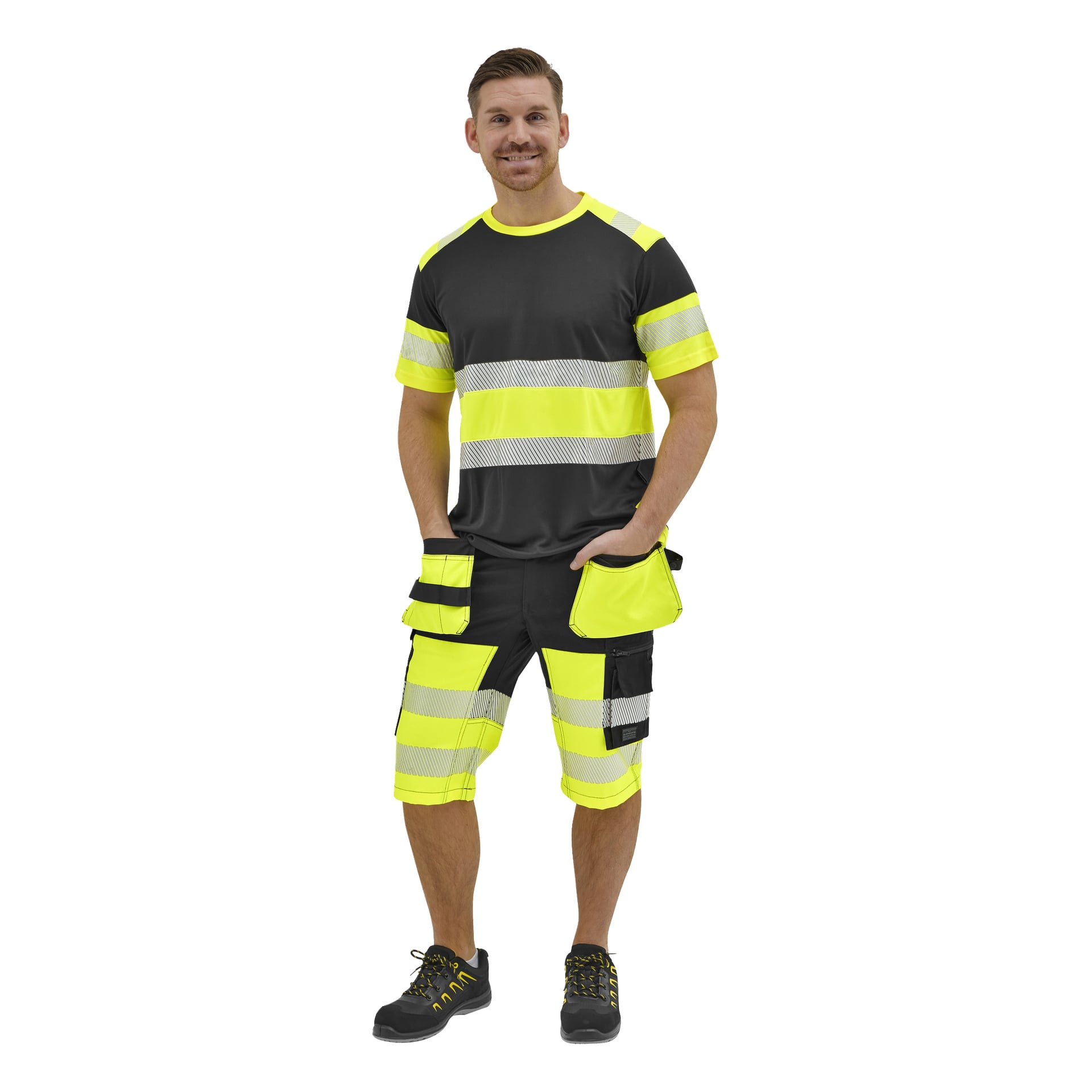 En man ler med händerna i fickorna, klädd i en svart och neongul kortärmad skjorta och matchande cargoshorts.