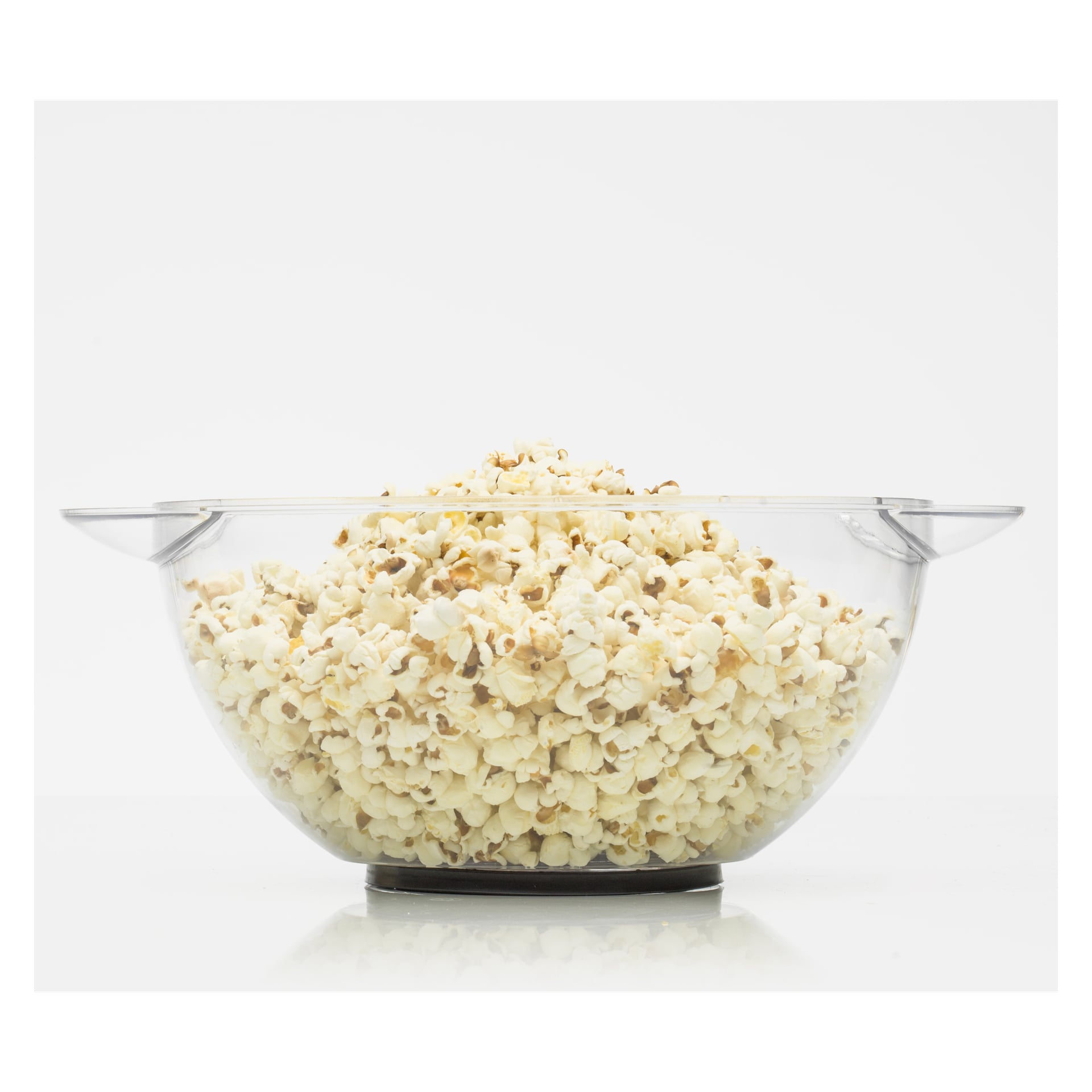 En glasskål fylld med popcorn vilar på en vit yta.