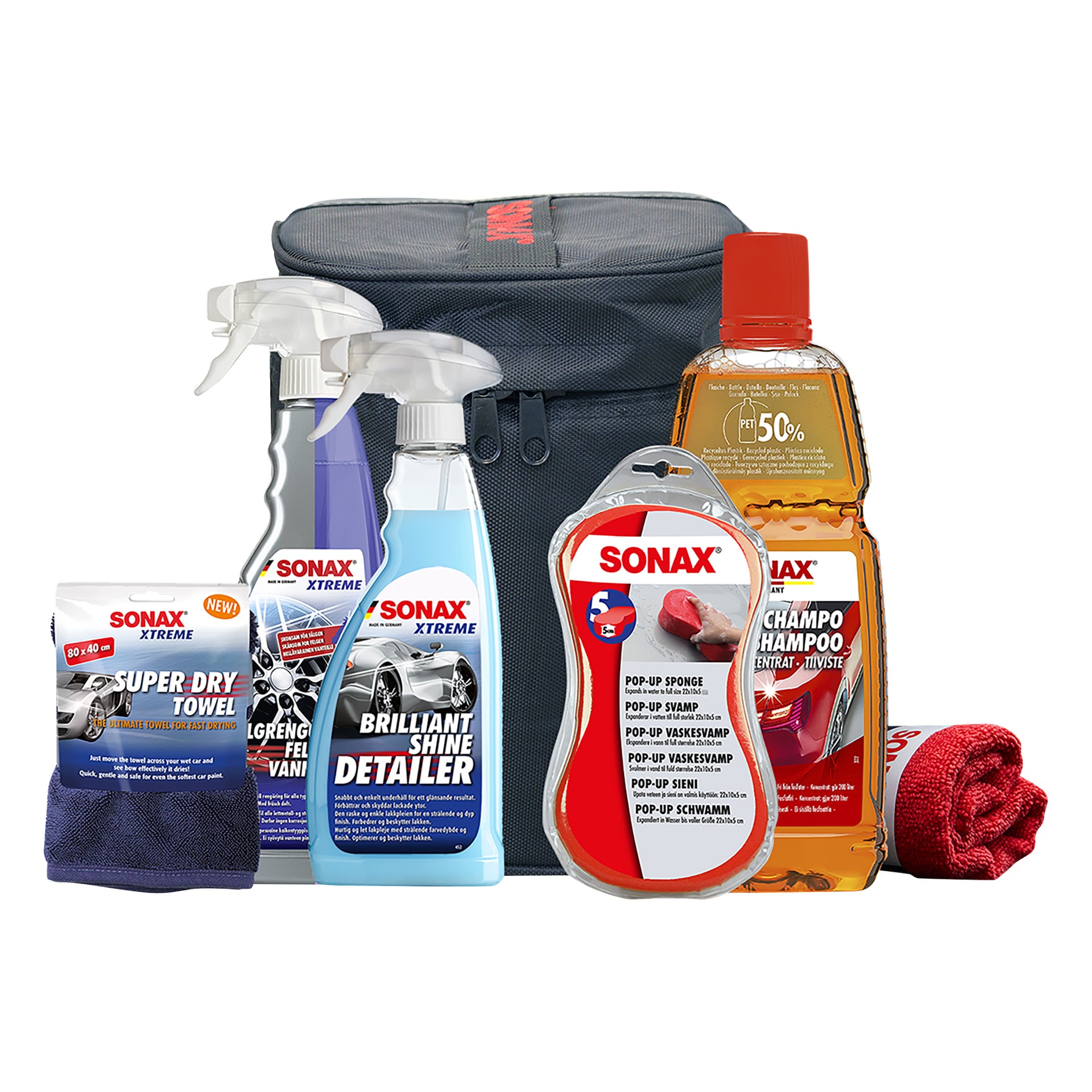 SONAX Car Care Kit – Innvendig sett med seks deler, inkludert sprayflasker, sjampo, rengjøringshåndklær, en rød mikrofiberklut, en pop-up svamp og en grå bærepose – alt er pent plassert i oppreist posisjon.
