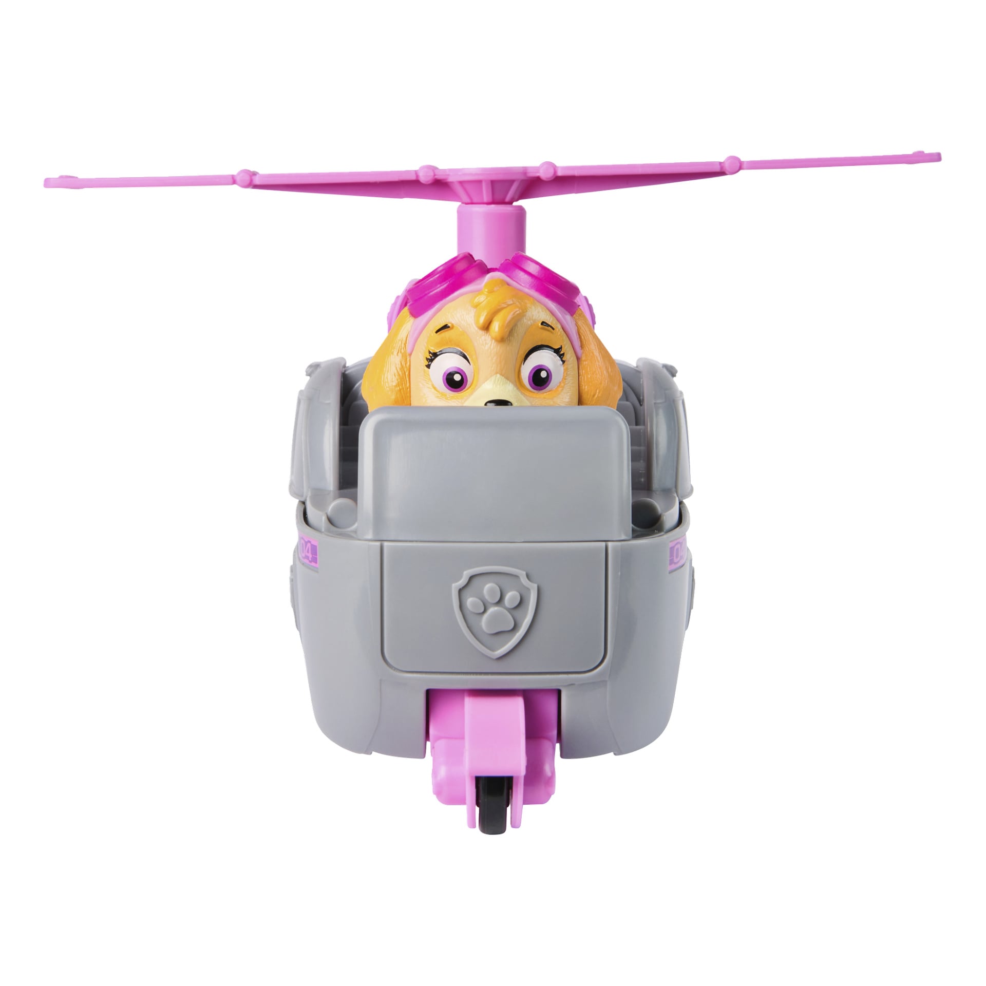 Paw Patrol Skye -helikopterilelu esittelee ruskean koirahahmon, jolla on vaaleanpunaiset suojalasit ja joka istuu ajoneuvossa, jossa on vaaleanpunaiset roottorit ja yksityiskohtia. Koira näkyy osittain peitettynä harmaan kilvenmuotoisen paneelin edessä, jossa on tassunjälki -tunnus.