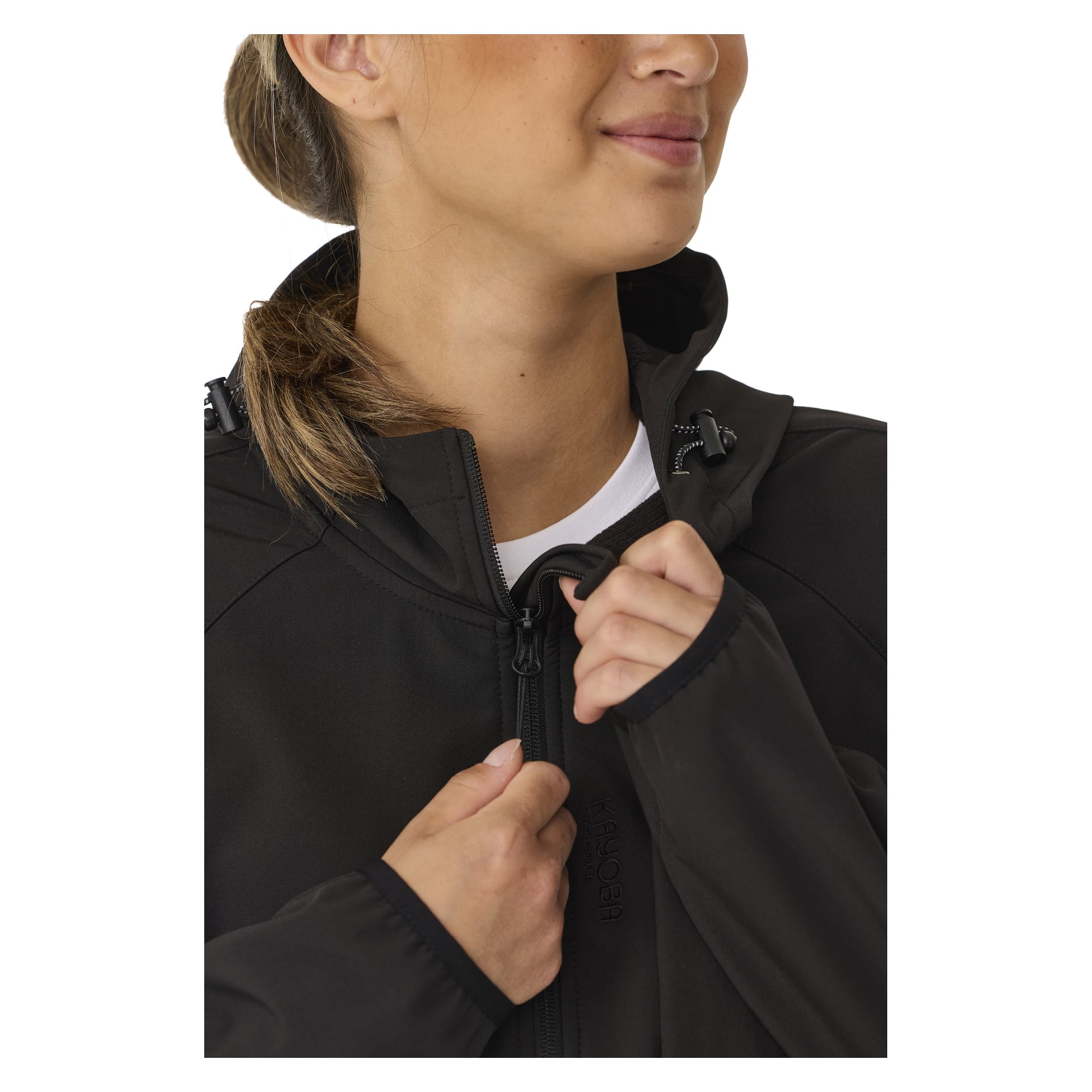 Eine Person mit heller Haut und zurückgebundenem braunem Haar wird gezeigt, wie sie die Kayoba Outdoor Women's Softshell-Jacke Hede, die eine Kapuze hat, zuzieht. Das Bild ist beschnitten, um nur das untere Gesicht, den Hals und die Hände zu zeigen.