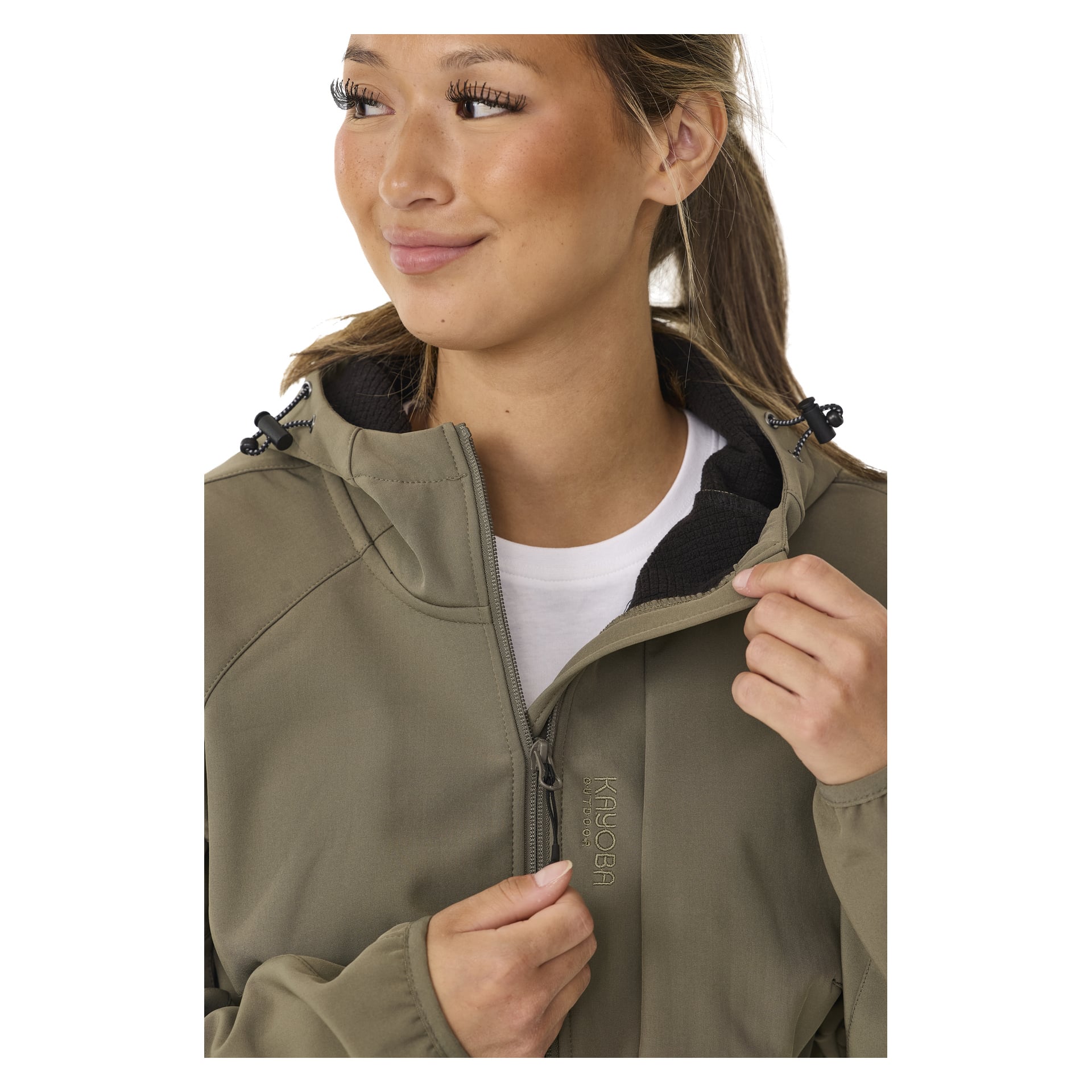 Jemand zieht eine olivgrüne Kayoba Outdoor Hede Damensoftshelljacke mit Fleecefutter, Kapuze und schwarzem Innenraum zu. Sie tragen darunter ein weißes Hemd und blicken leicht zur Seite.
