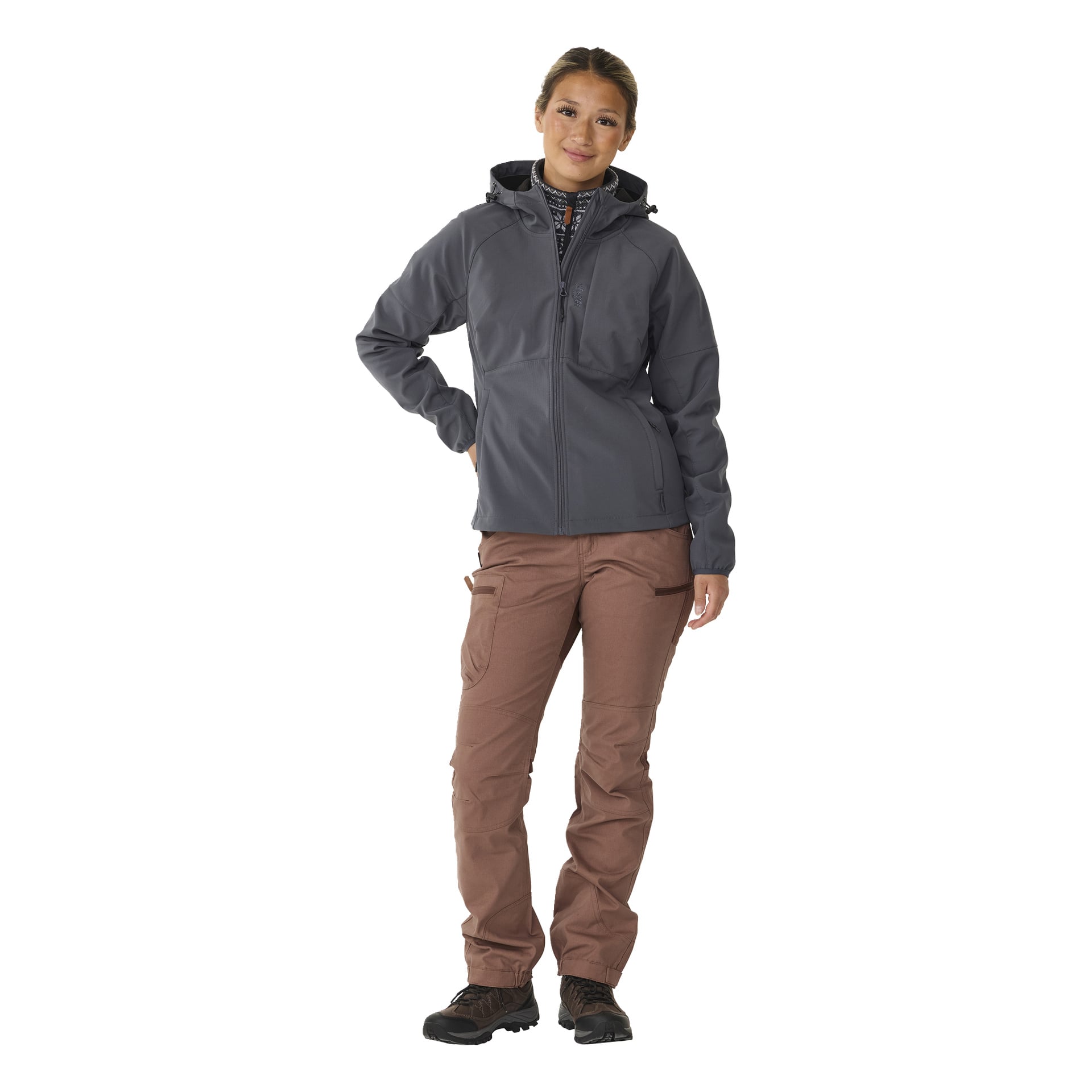 Eine Person steht mit dem Rücken nach vorne in einer grauen Kayoba Outdoor Women's Softshell-Jacke Hede, brauner Cargohose und schwarzen Wanderschuhen. Eine Hand ist auf der Hüfte, die andere hängt natürlich an der Seite.