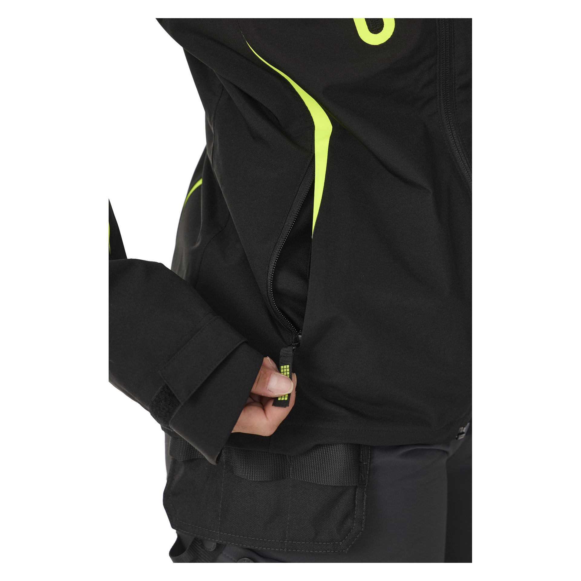 En person som bär Bluewear Women's stretchjacka Rebecca i svart med neongula detaljer drar upp en ficka med dragkedja. Bilden visar bara nedre bålen, handen och en del av armen.