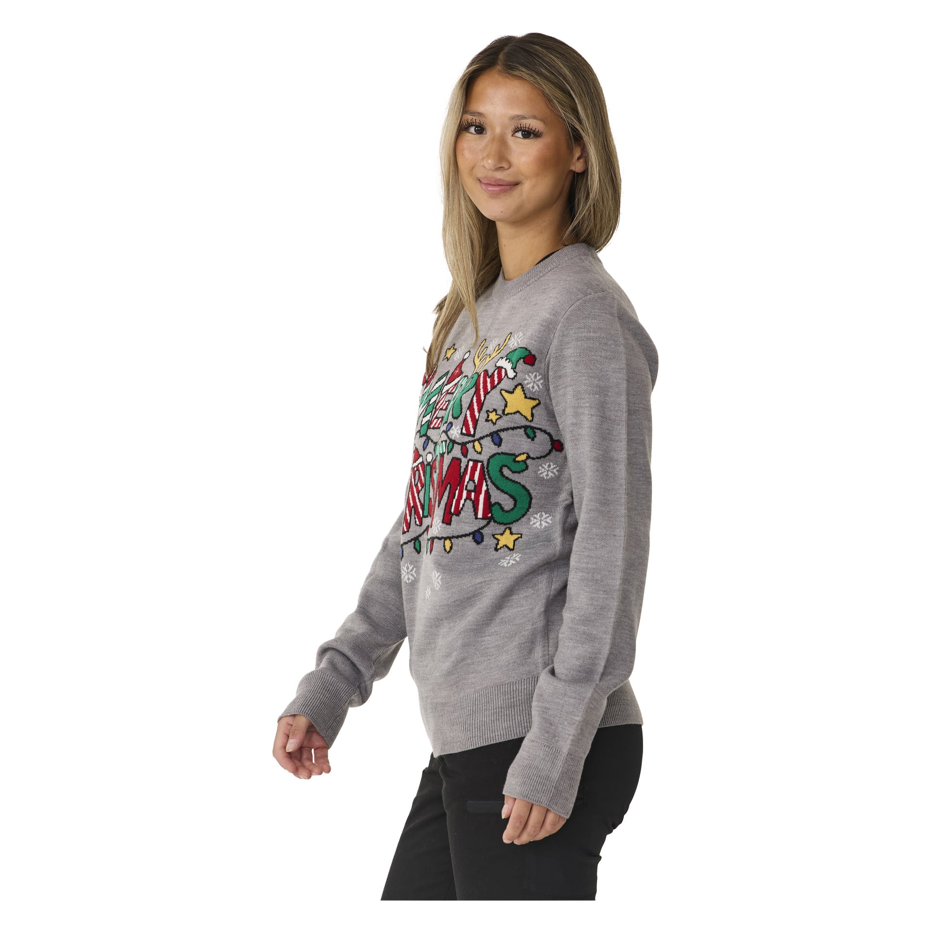 En kvinne med langt hår bærer Bluewear-juletoppen, en grå genser dekorert med sukkertøystenger, stjerner, snøfnugg og fargerike lyslenker. Hun står på skrå og smiler mykt.