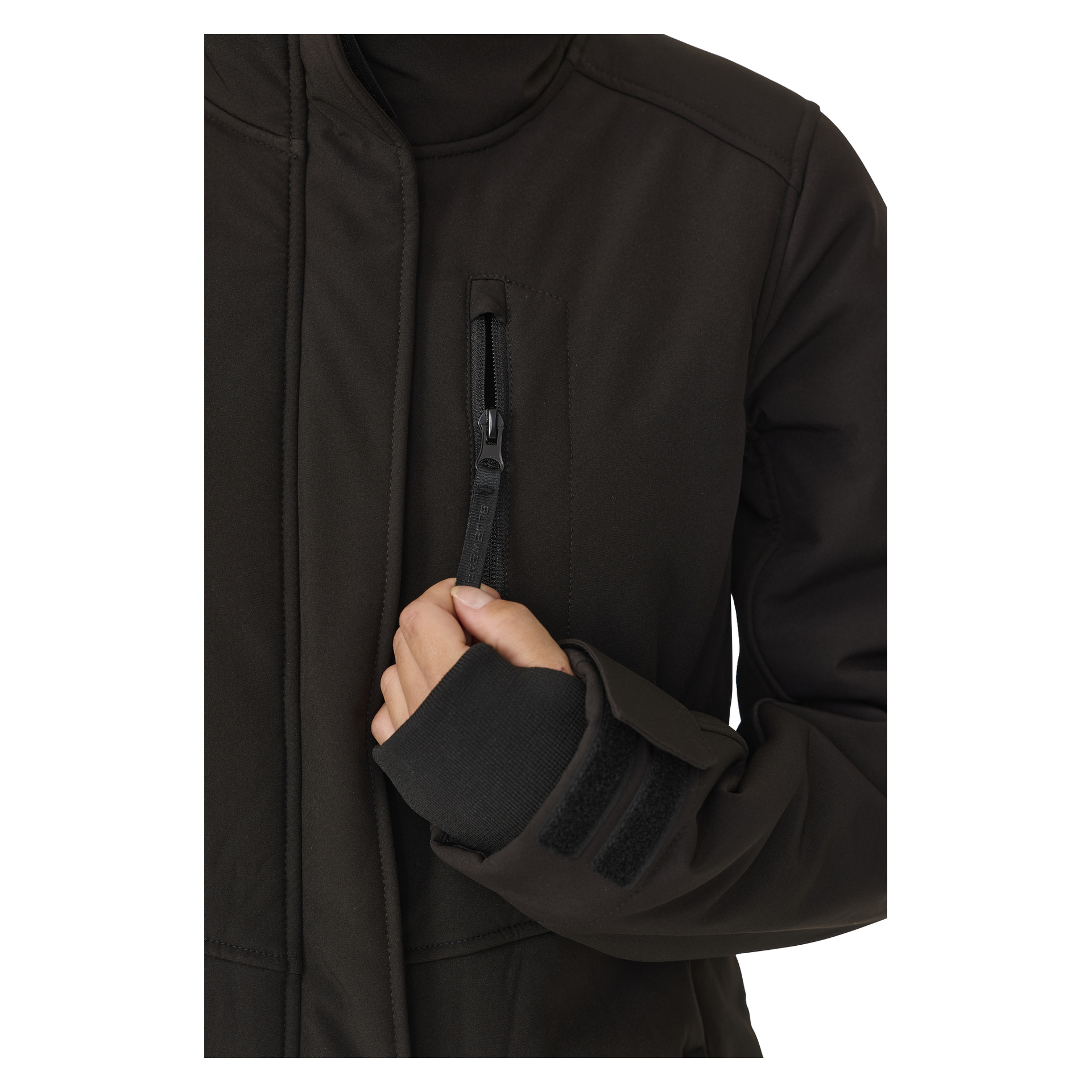 Henkilö mallintaa Bluewear Womanin pitkää Gunnel-softshell-takkia, vetäen pystysuoran rintataskun oikealla kädellään. Takissa on korkea kaulus ja säädettävät tarranauhat.