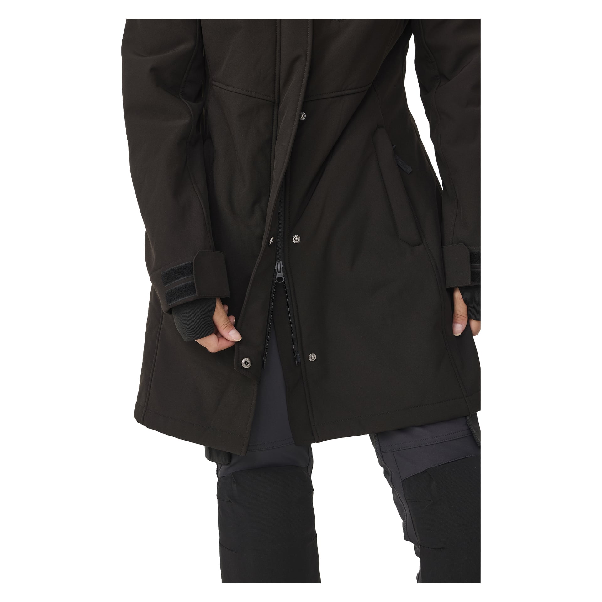 Ihmisen alavartalo on näkyvissä, ja hänellä on päällään Bluewear Woman's Softshell Jacket, pitkä Gunnel-tyylinen, napit ja vetoketjullinen etuosa. Heillä on myös tummat housut ja mustat hanskat, ja he pitävät takkia vetoketjun lähellä yhdellä kädellä.