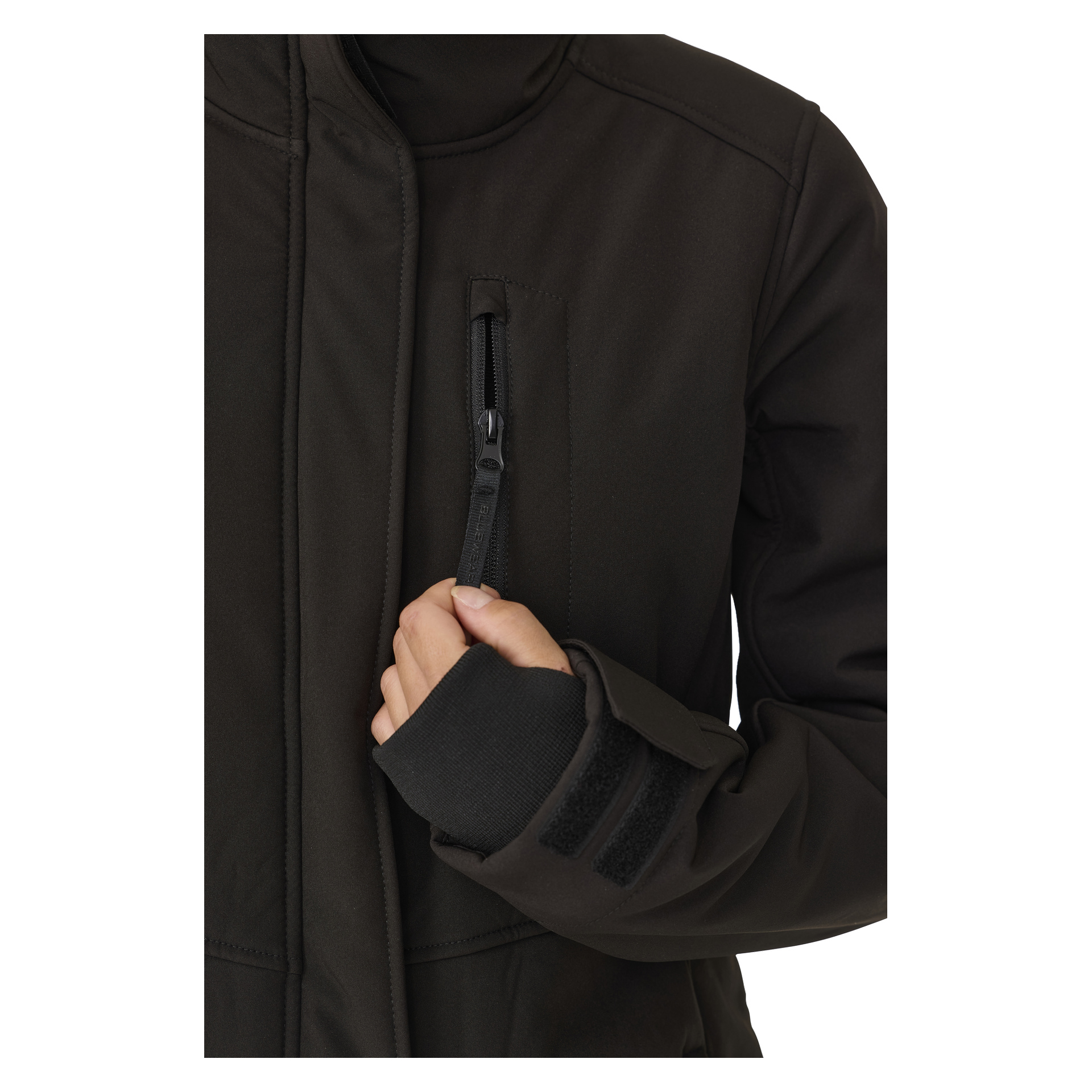 Henkilö, joka on pukeutunut Bluewear Womanin pitkään Gunnel-softshell-takkiin, avaa pientä taskua rinnassa. Takissa on korkea kaulus ja tarranauhalliset rannekkeet. Näkyvissä on vain heidän vartalonsa ja toinen käsi.