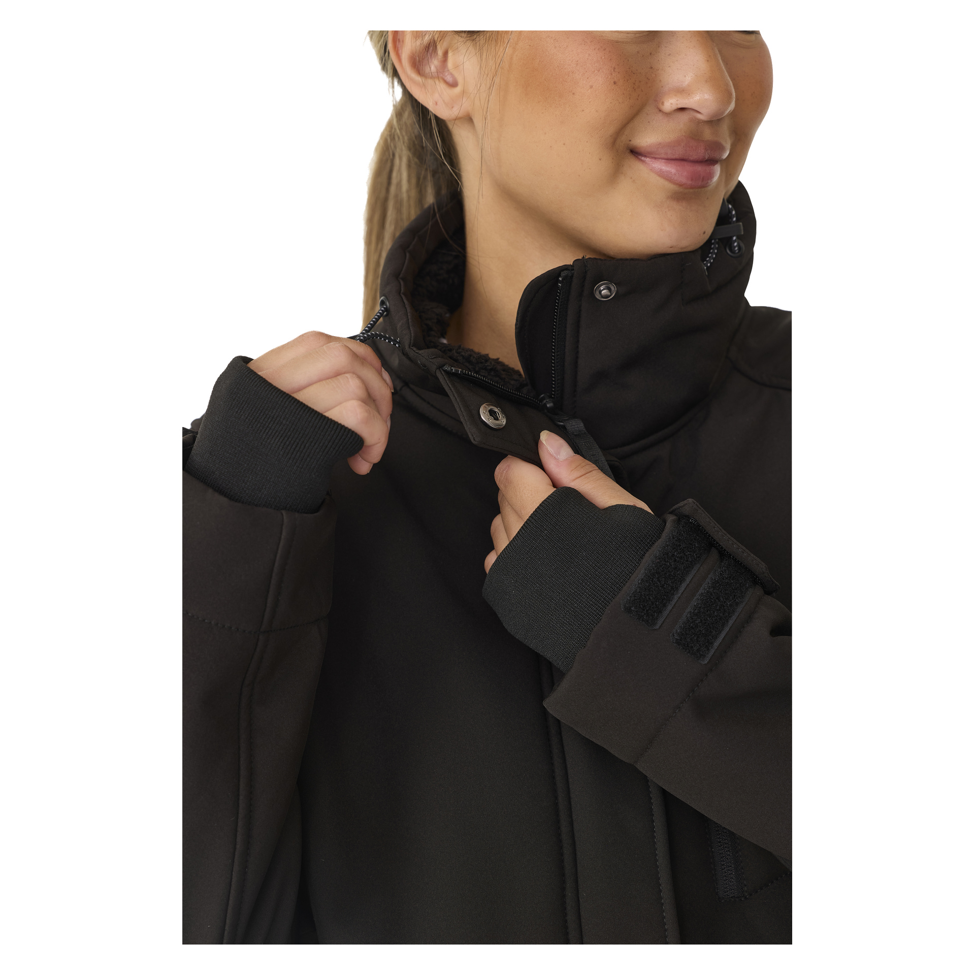 Joku kiinnittää naisten pitkän Gunnel-softshell-takin kauluksen ja napin kiinni Bluewearilta. Takki on tummanvärinen, siinä on korkea kaulus ja hihansuissa on tarranauharemmit. Osittain näkyvät heidän kasvonsa ja toinen käsi.