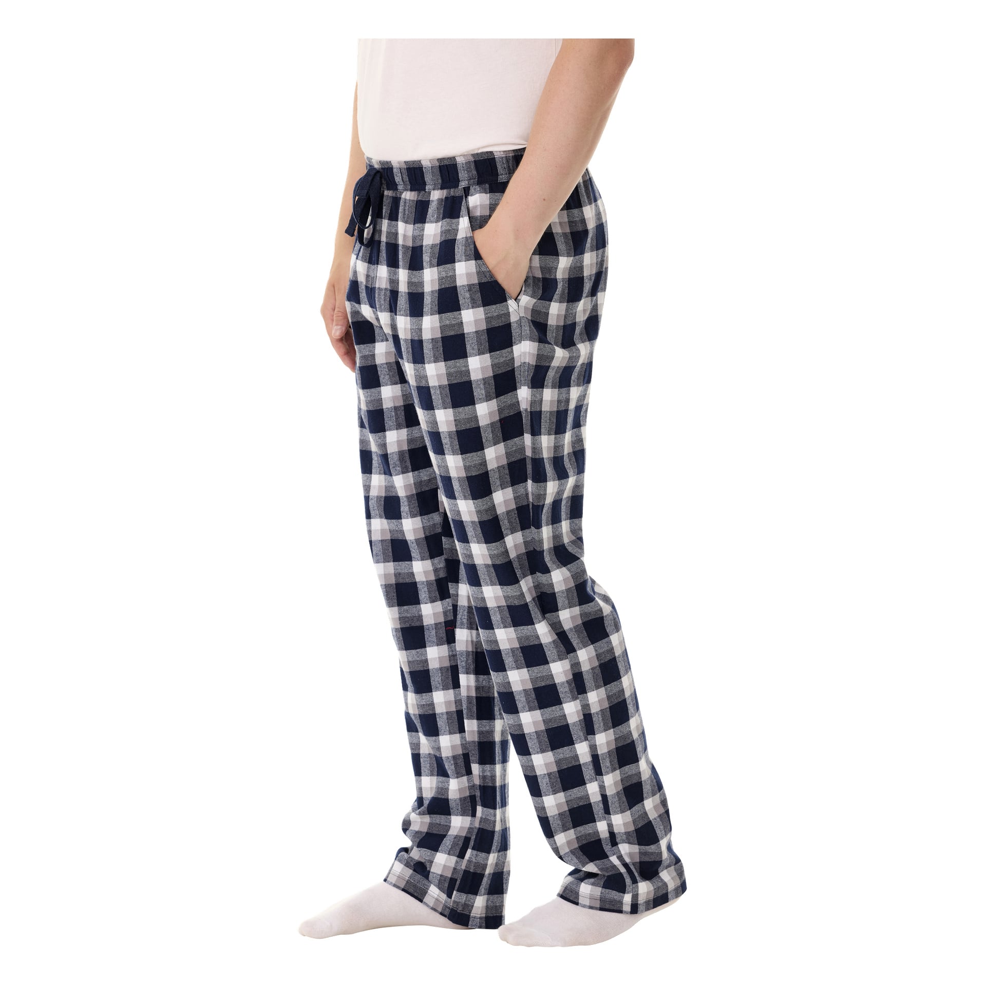 En person visas från midjan och ner i en sidovy, iklädd Bluewear Pyjamasbyxor med blått och vitt rutigt mönster, vita strumpor och en enkel vit skjorta. Deras händer är nedstoppade i fickorna på pyjamasbyxorna.