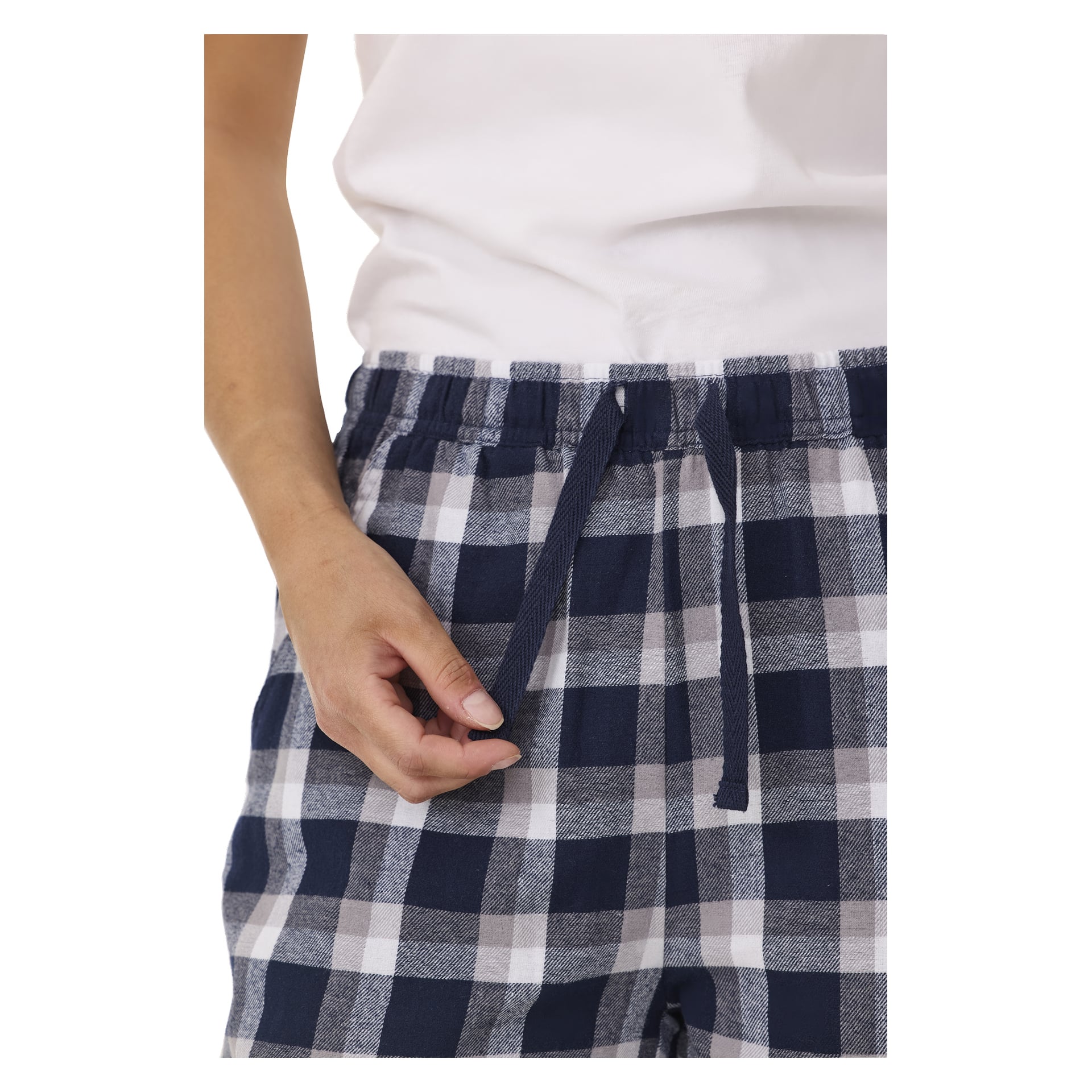 Man justerar dragskoen på Bluewear pyjamasbyxor med ett blåvitt rutigt mönster, tillsammans med en vit skjorta. Miljön är enkel och fri från distraktioner.