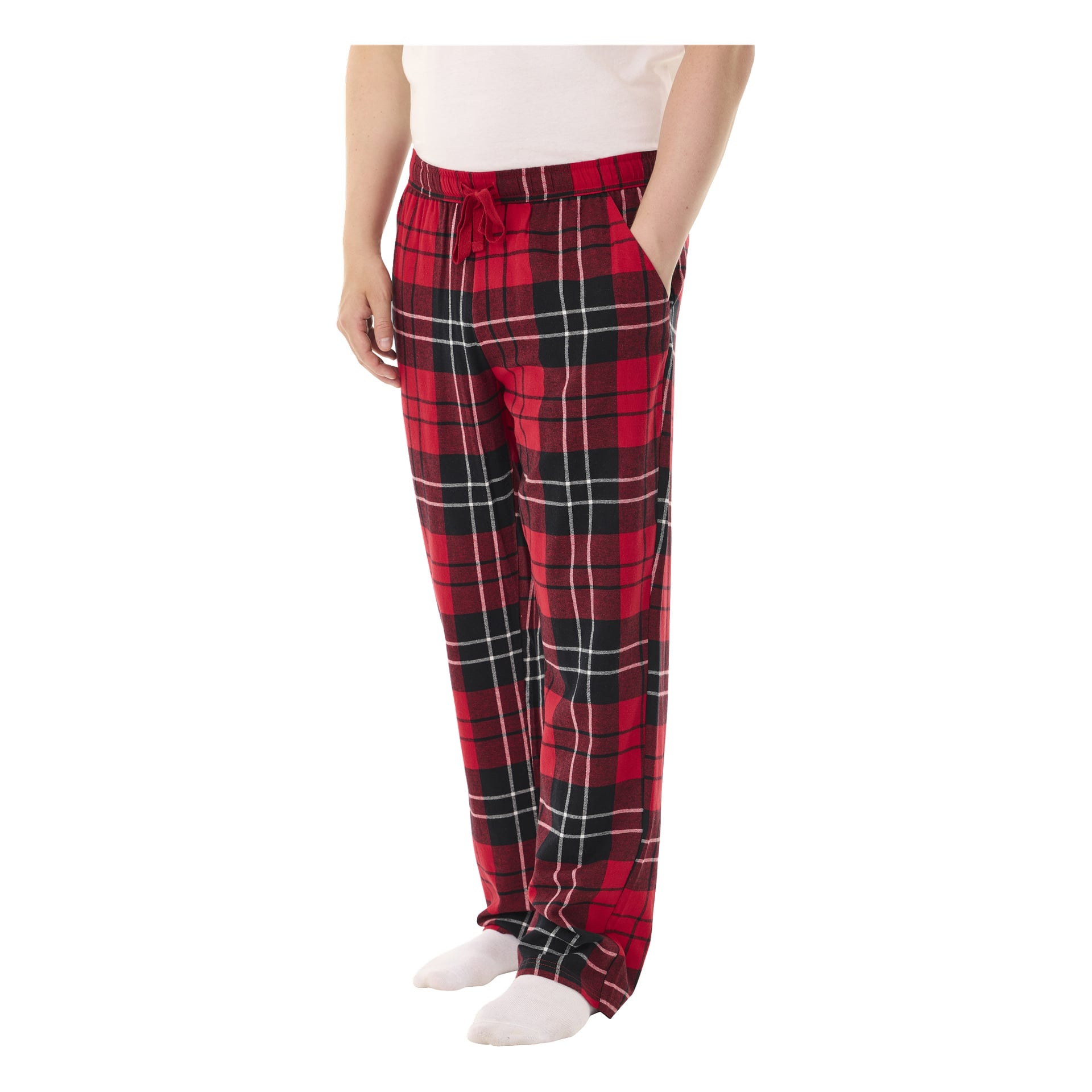 En person modellerar Bluewear pyjamasbyxor med röd och svart rutig design, händerna instuckna i fickorna, tillsammans med en vit topp och vita strumpor.