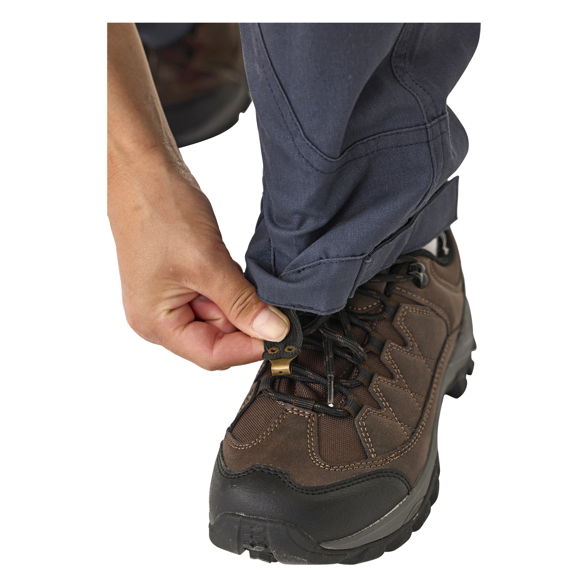 Man glir opp mansjetten på Kayoba Outdoor Leisure damebukser Älvdalen 2.0, og fester den rundt en brun tursko med svarte lisser.