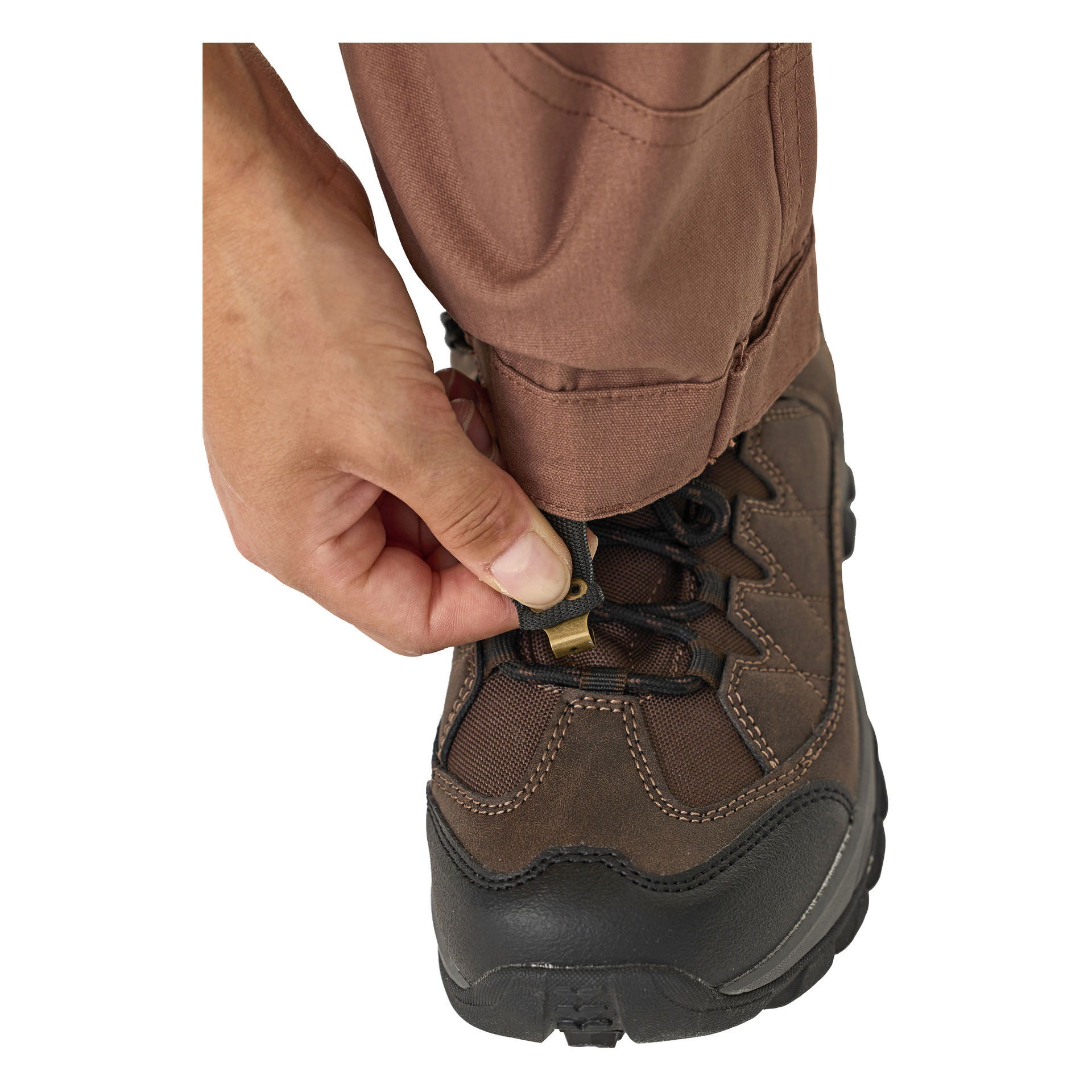 En person kledd i brune Kayoba Outdoor Leisure-bukser, dame Älvdalen 2.0, trekker snoren over en matchende brun tursko og fester den med en svart og messingknapp.