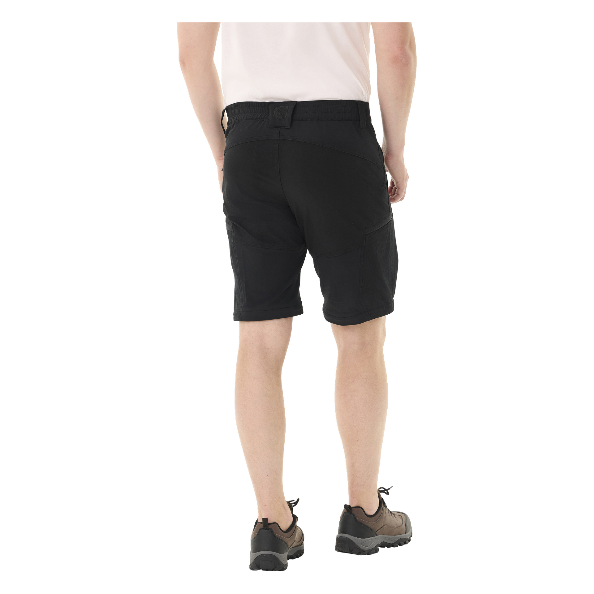 En person vänder blicken bort från kameran, klädd i svarta Kayoba Outdoor Men's zip-off-byxor Abisko, en ljus skjorta och svarta skor med mörka strumpor.