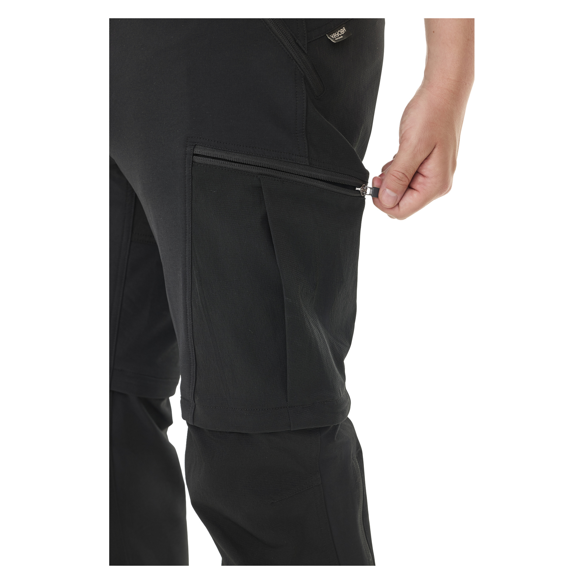 En person visas när han drar ner dragkedjan på herrarnas Zip-Off Outdoor Trousers Abisko från Kayoba Outdoor. Fokus ligger på handen, dragkedjan och fickan, med resten av byxorna synliga.