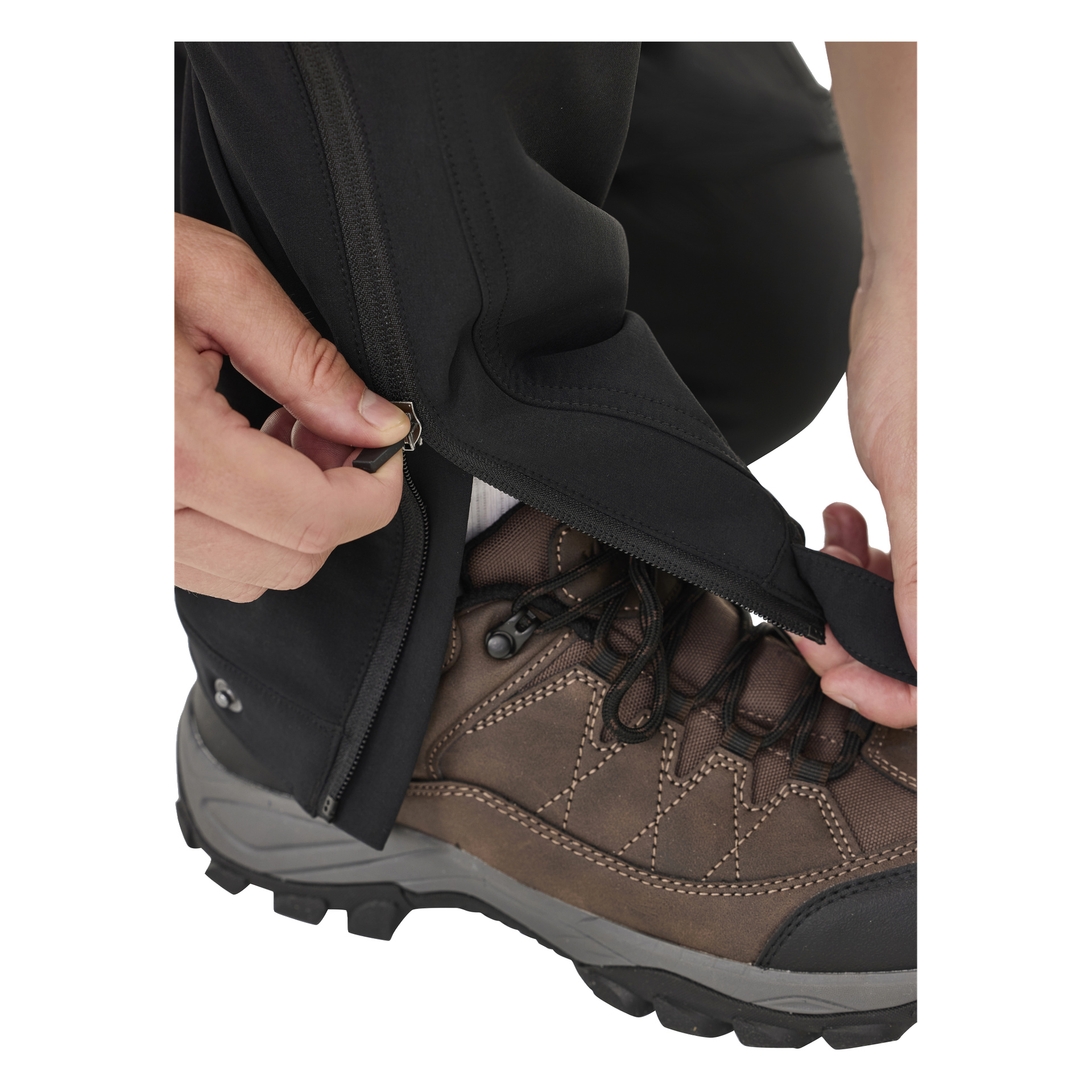 Jemand zieht den unteren Teil der Kayoba Outdoor Men's Outdoor-Hose, Abisko, über einen braunen Wanderstiefel und lenkt so die Aufmerksamkeit auf die Hände, den Reißverschluss, das Hosenbein und den Stiefel.