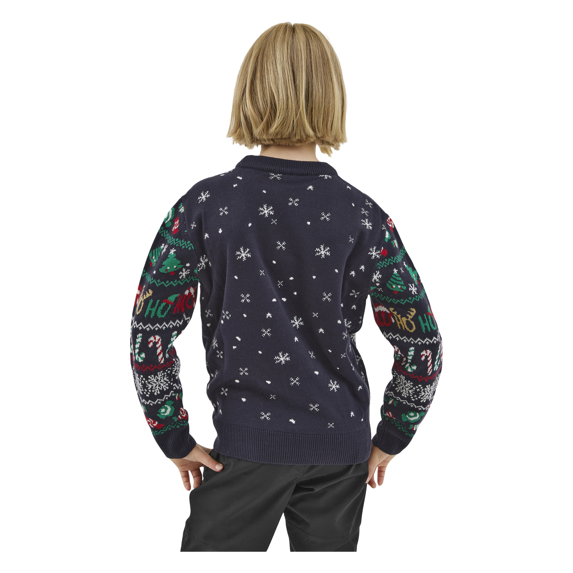Ett blont barn står med ryggen mot betraktaren, händerna på höfterna, klädd i en Bluewear Children's jultröja dekorerad med snöflingor, julgranar, polkagrisar och texten "Ho Ho Ho" på ärmarna. Barnet har svarta byxor på sig.