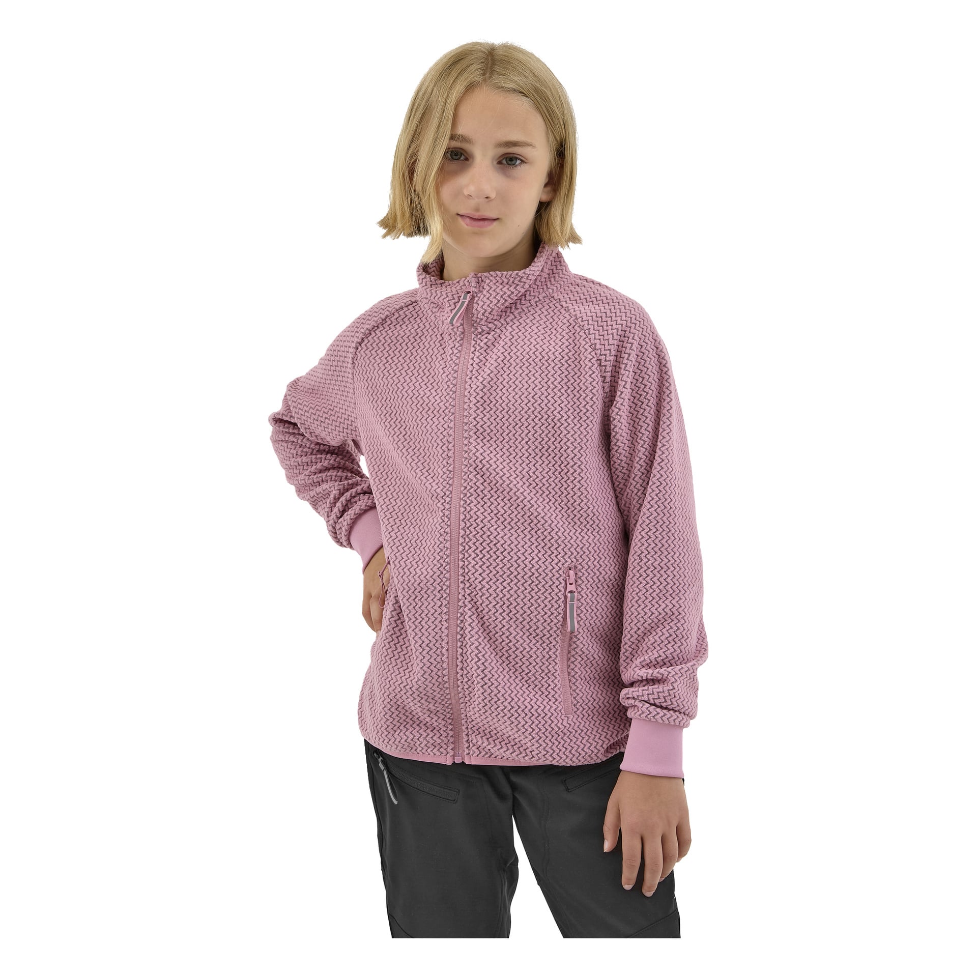 Lapsi, jolla on vaaleat, olkapäille ulottuvat hiukset, esittelee vaaleanpunaisen Kayoba Outdoor Children's Fleece-takin Ombergin, jossa on teksturoitu vetoketjullinen tyyli. Lapsi yhdistää sen tummiin housuihin ja poseeraa itsevarmasti, toinen käsi lanteilla.
