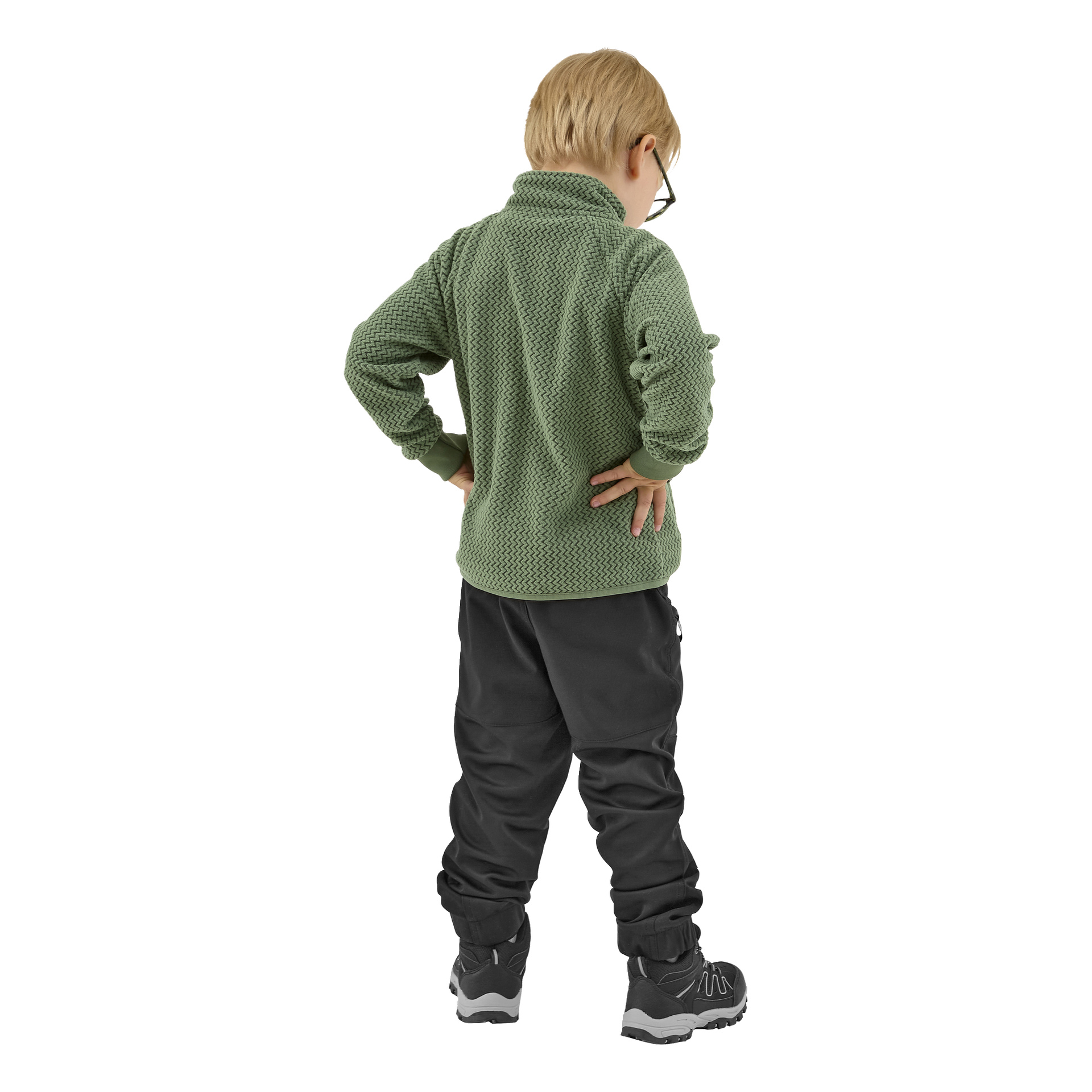 Nuori lapsi, jolla on vaaleat hiukset ja silmälasit, seisoo selkä kameraan päin, kädet lanteilla. Lapsi on pukeutunut vihreään Kayoba Outdoor Children's Fleece -takkiin, mustiin housuihin ja mustiin urheilukenkiin, joissa on valkoiset pohjat.
