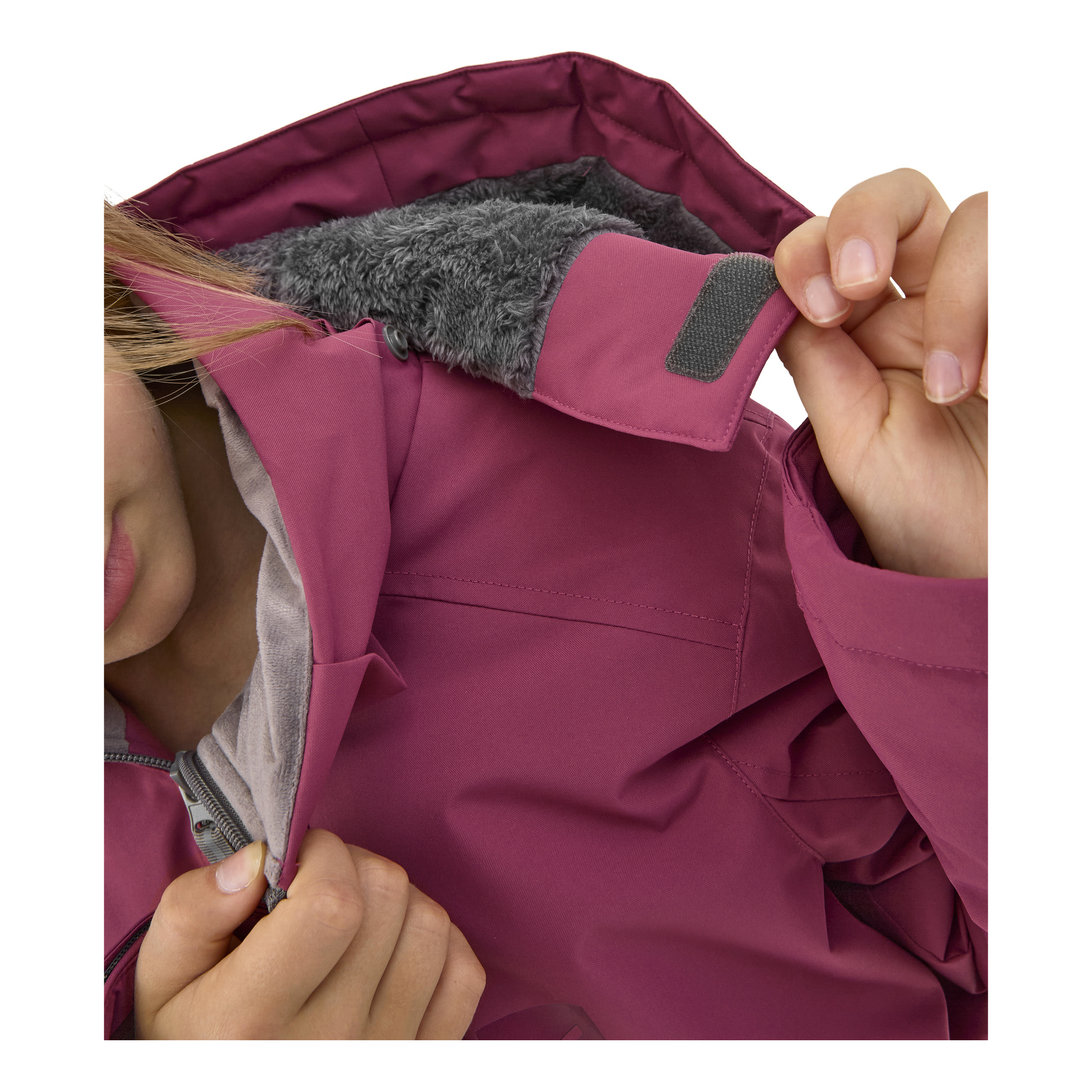 Ett barn klädd i en magenta Kayoba Outdoor Children's vinterjacka Kläppen lyfter upp en kardborrelåst flik vid kragen, vilket visar det grå fleecefodret och knäppningsdetaljerna inuti.
