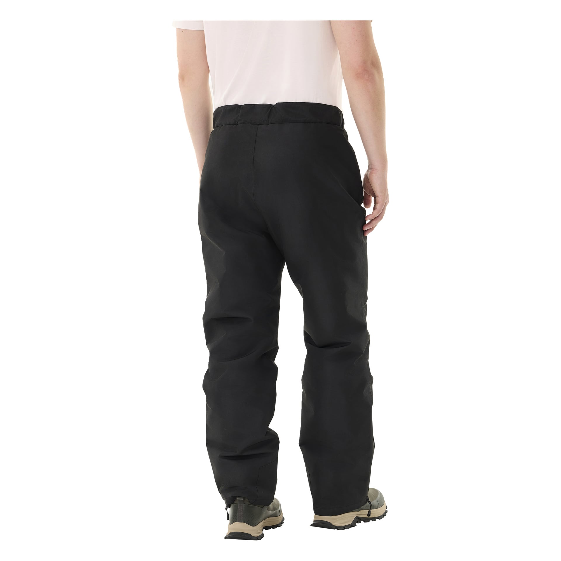 Henkilö kuvataan olkapäistä alaspäin, selin poispäin, pukeutuneena lyhythihaiseen valkoiseen paitaan, mustiin Kayoba Outdoor Padded Kiruna 2.0 -housuihin miehille sekä beigeihin kenkiin, joissa on mustat pohjat.