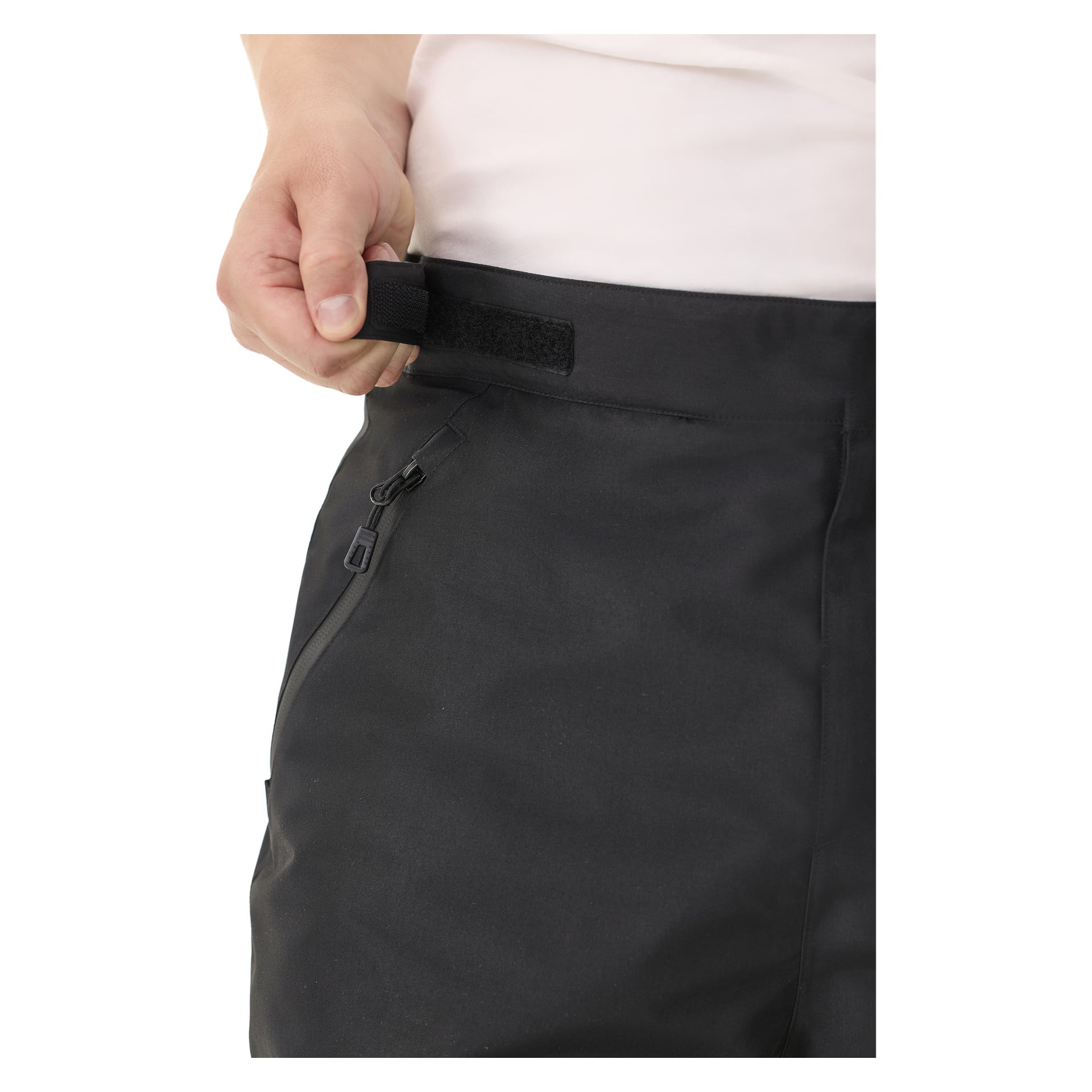 Joku kiristää yhdellä kädellä Kayoba Outdoor Padded Trousers for Men Kiruna 2.0:n vyötäröltä tarranauhalla, ja housuissa näkyy vetoketjullinen tasku.