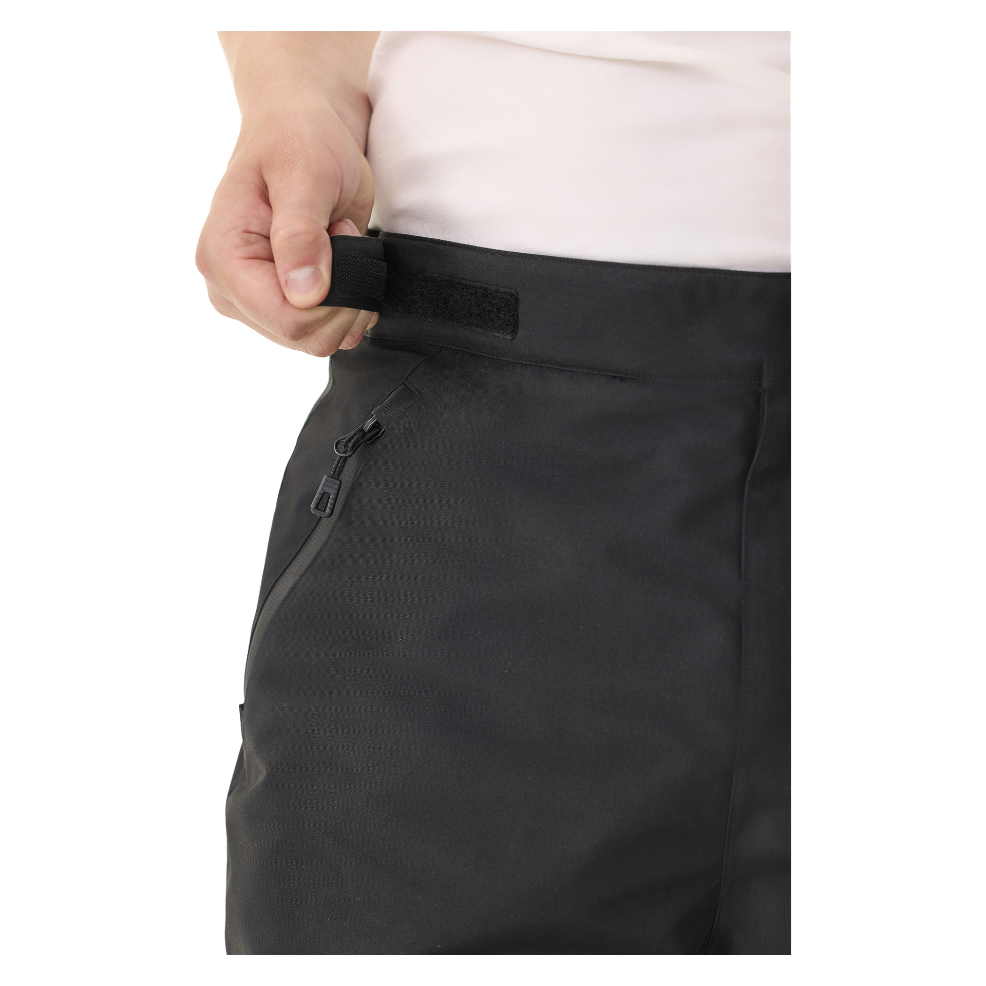 Jemand benutzt eine Hand, um die Kayoba Outdoor Padded Trousers for Men Kiruna 2.0 mit einem Velcro-Riemen an der Taille festzuziehen, während an der Hose eine Reißverschlusstasche zu sehen ist.