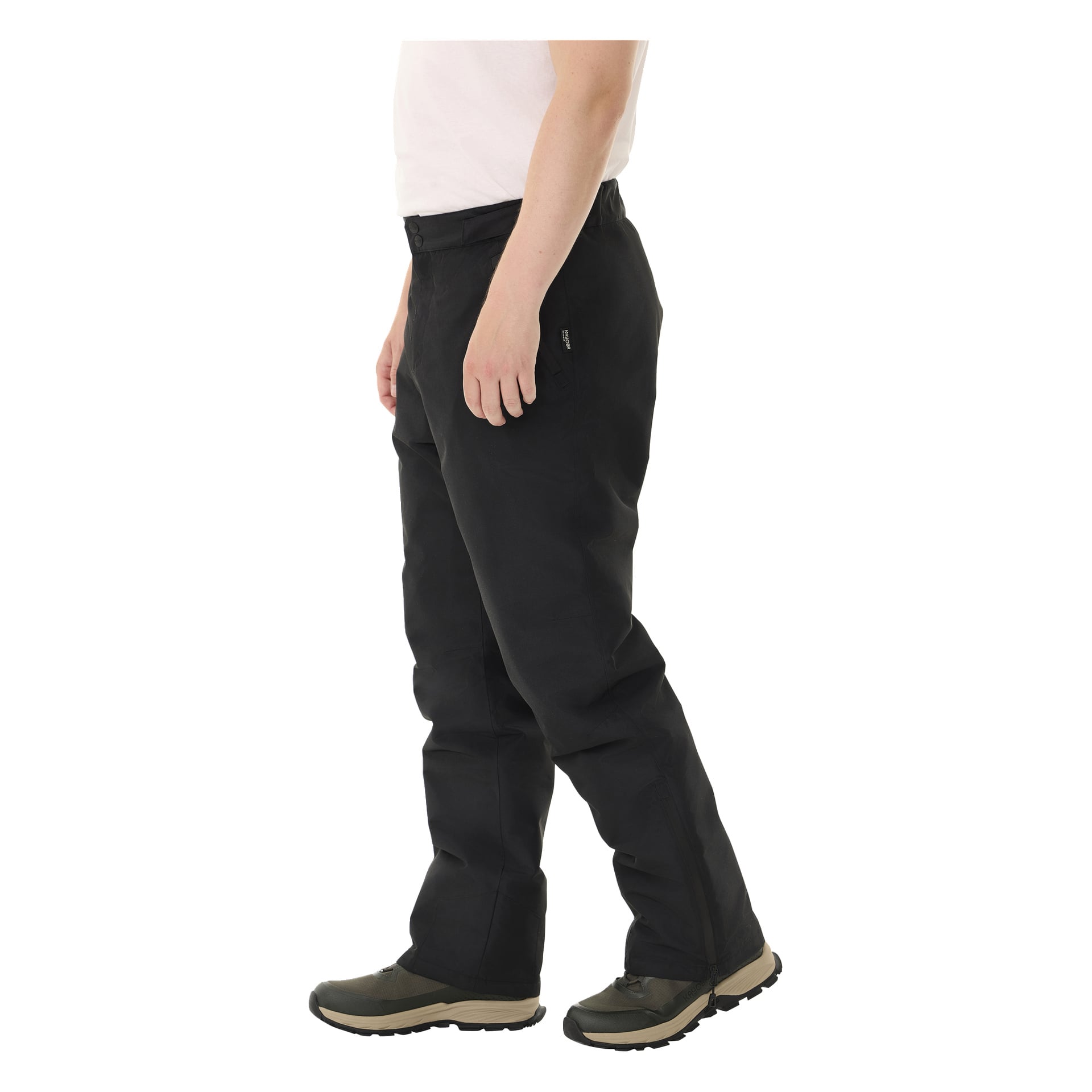 Henkilö, joka on pukeutunut valkoiseen paitaan, Kayoba Outdoor Padded Kiruna 2.0 -mustat housut miehille sekä vihreät ja mustat kengät seisoo sivuttain vasen käsivarsi luonnollisesti vierellä.