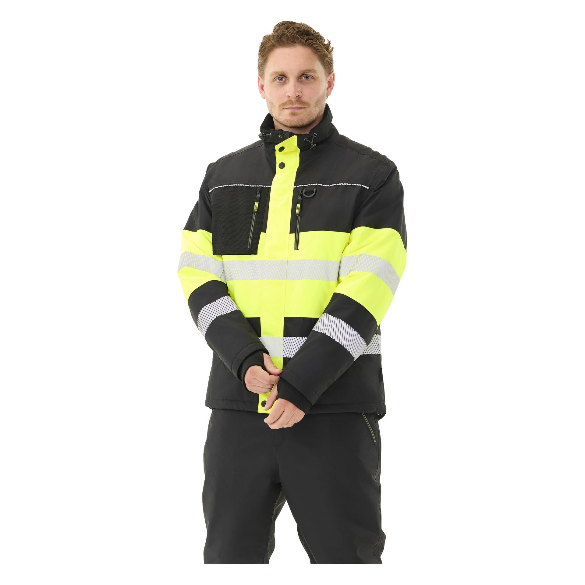 En person med kort lysebrunt hår står vendt fremover, iført Bluewear Padded Hi-Vis-jakke Lawson i svart og gult med reflekterende striper, sammen med svarte bukser. Hendene deres er foldet foran seg.