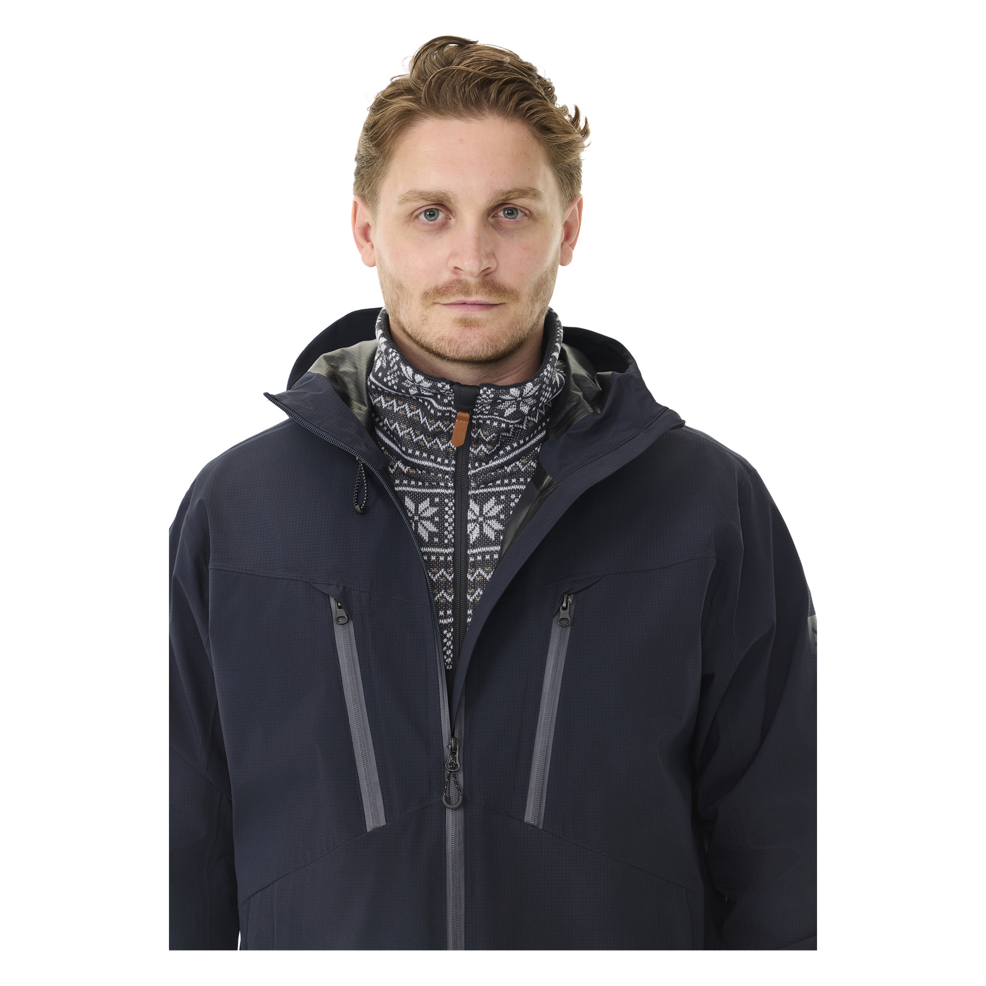 En mann med kort lysebrunt hår bærer Kayoba Outdoor Men's Sarek shell-jakke, en marineblå glidelås-look, lagt over en genser med høy krage og et svart-hvitt geometrisk design.