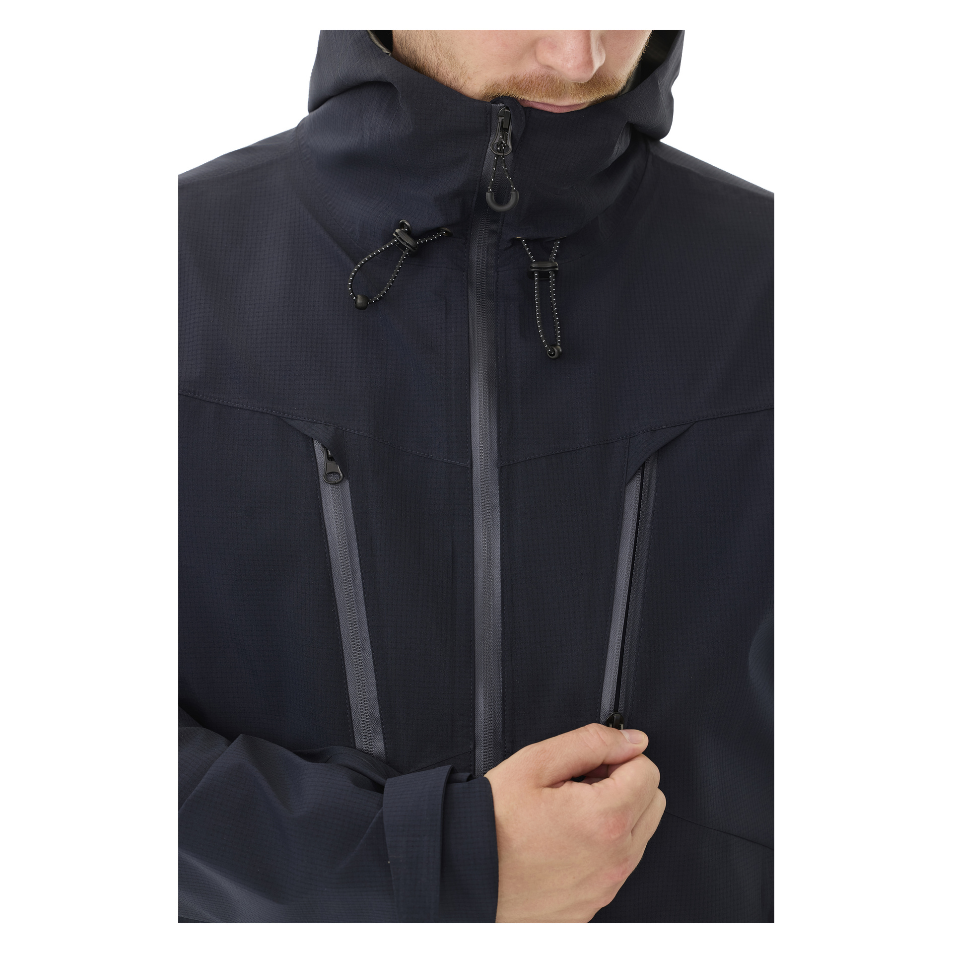 Sett fra skuldrene og ned, bøyer en person hodet mens de glir igjen en vertikal brystlomme foran på Kayoba Outdoor Men's shelljacket Sarek.