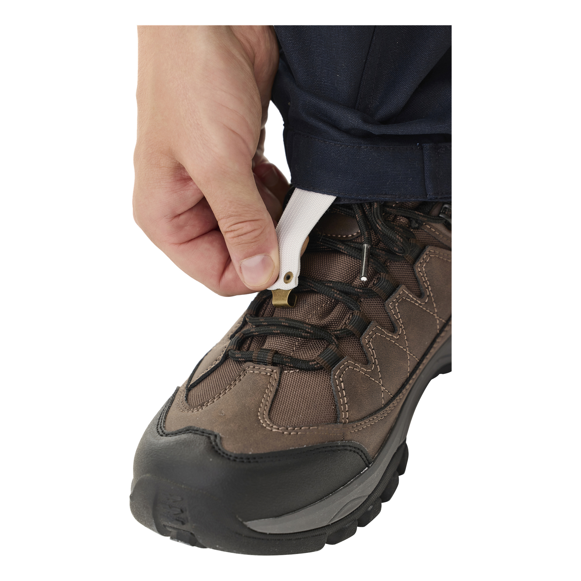 Osoba w spodniach Kayoba Outdoor Men's Älvdalen 2.0 przypina mały haczyk na końcu białego paska do sznurowadeł brązowego buta trekkingowego, podkreślając obecność buta, paska i ręki.
