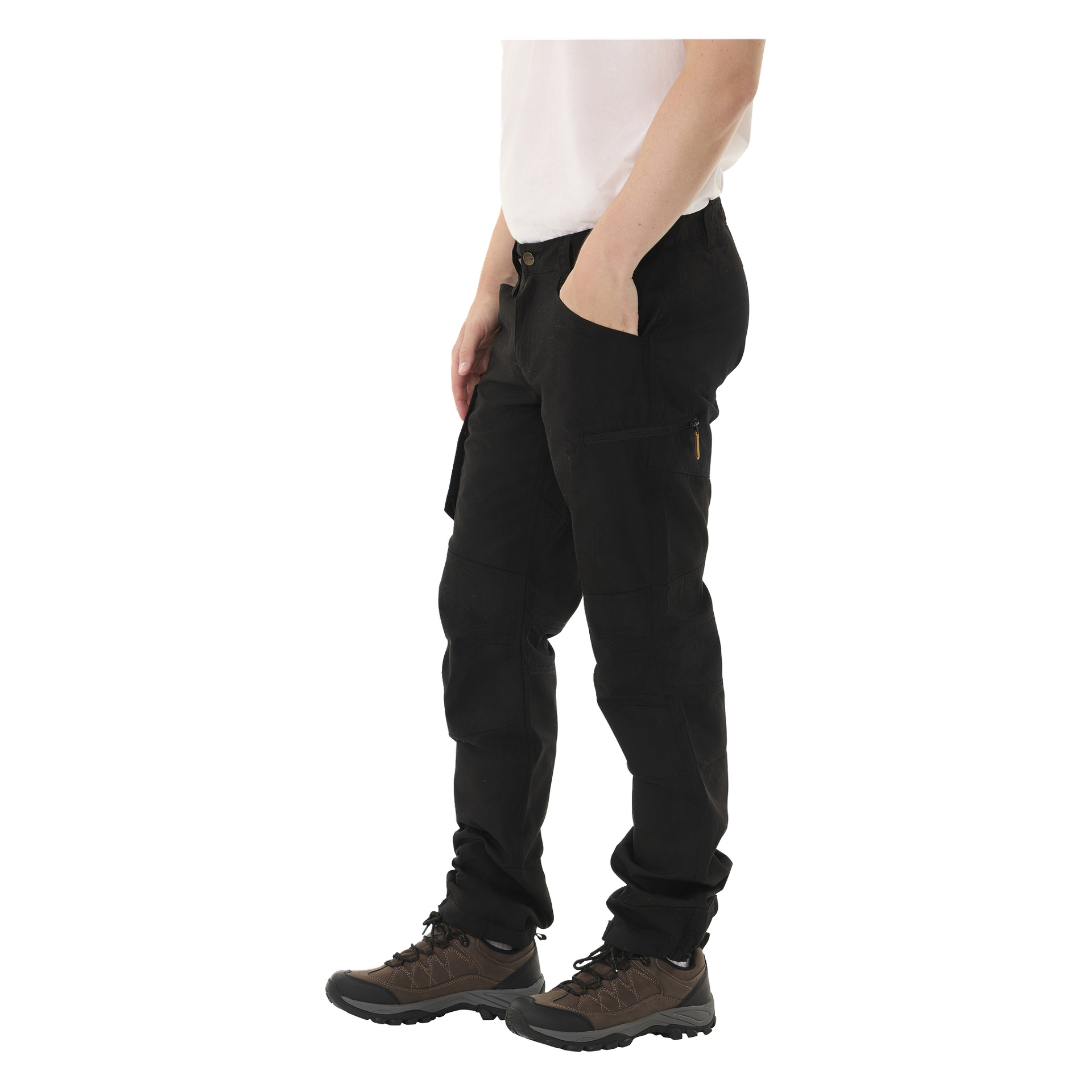 Eine Person, die ein weißes Hemd, schwarze Kayoba Outdoor Men Älvdalen 2.0 Hosen mit Seitentaschen und braunen Wanderschuhen trägt, steht mit einer Hand lässig in einer Tasche.