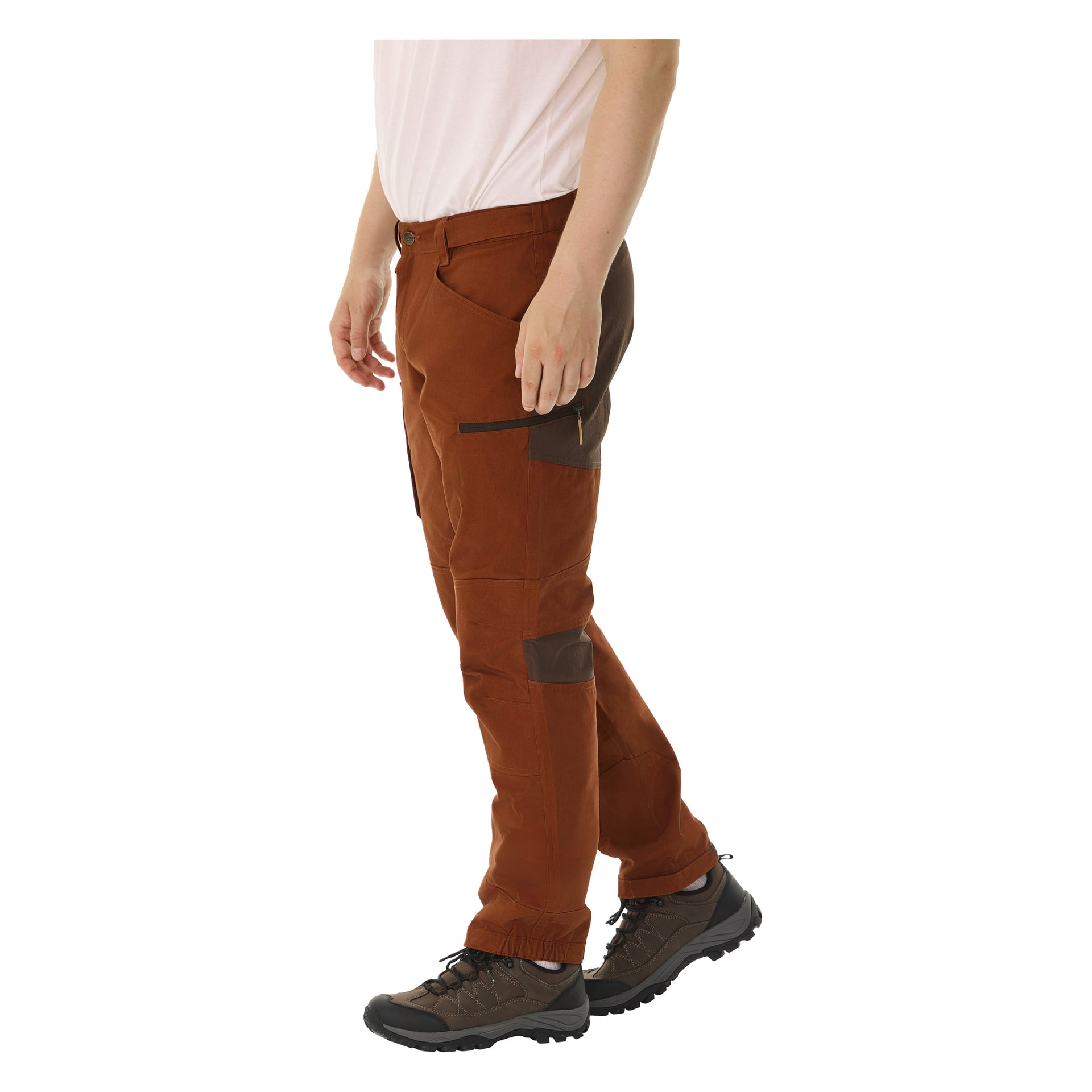 Sett fra siden er bare den nedre halvdelen av en persons kropp synlig. De er kledd i brune Kayoba Outdoor Men Älvdalen 2.0-bukser med flere lommer, glidelåsdetaljer og mørkere brune. Antrekket kompletteres med en hvit skjorte og mørkebrune tursko.