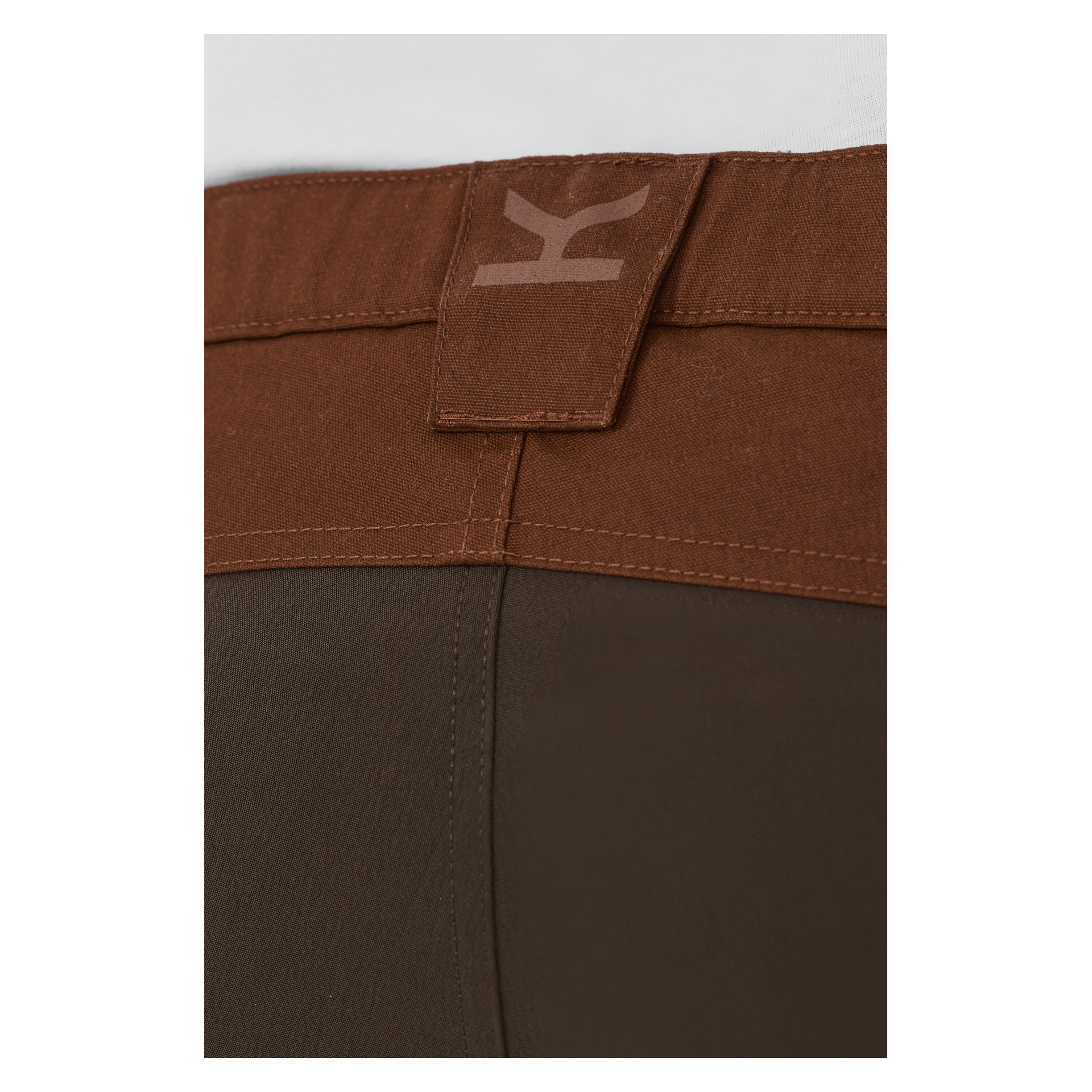 Detaljert bilde av Kayoba Outdoors Men Älvdalen 2.0-bukser i brunt, som fremhever belteløkken bak med en lysere preget K-logo. Linningen har en lysere brun tone sammenlignet med det dypere brune stoffet på buksens nedre del.