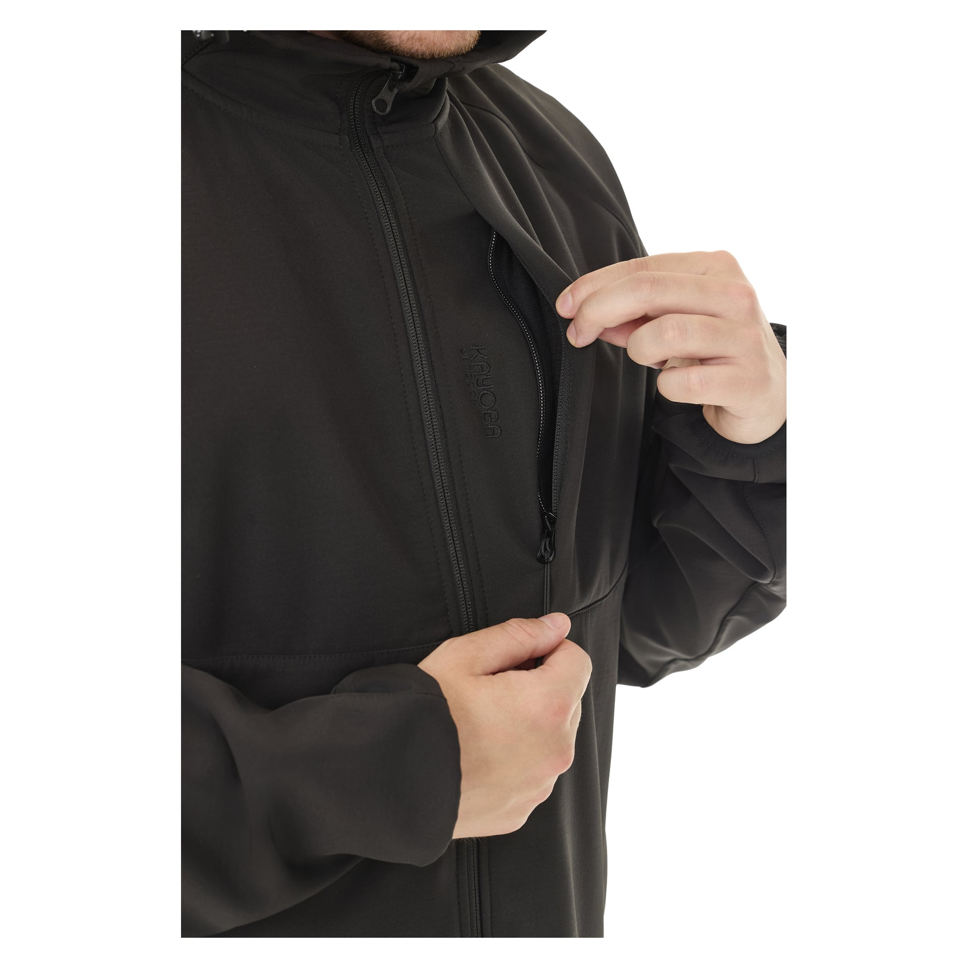 Osoba ubrana w czarną kurtkę Kayoba Outdoor Women's softshell z podszywką Hede używa prawej ręki, by otworzyć pionową kieszeń na paśmie zamekowym. Kurtka ma wysoki kołnierz, a na klapce zamka jest widoczne słowo "zamek".
