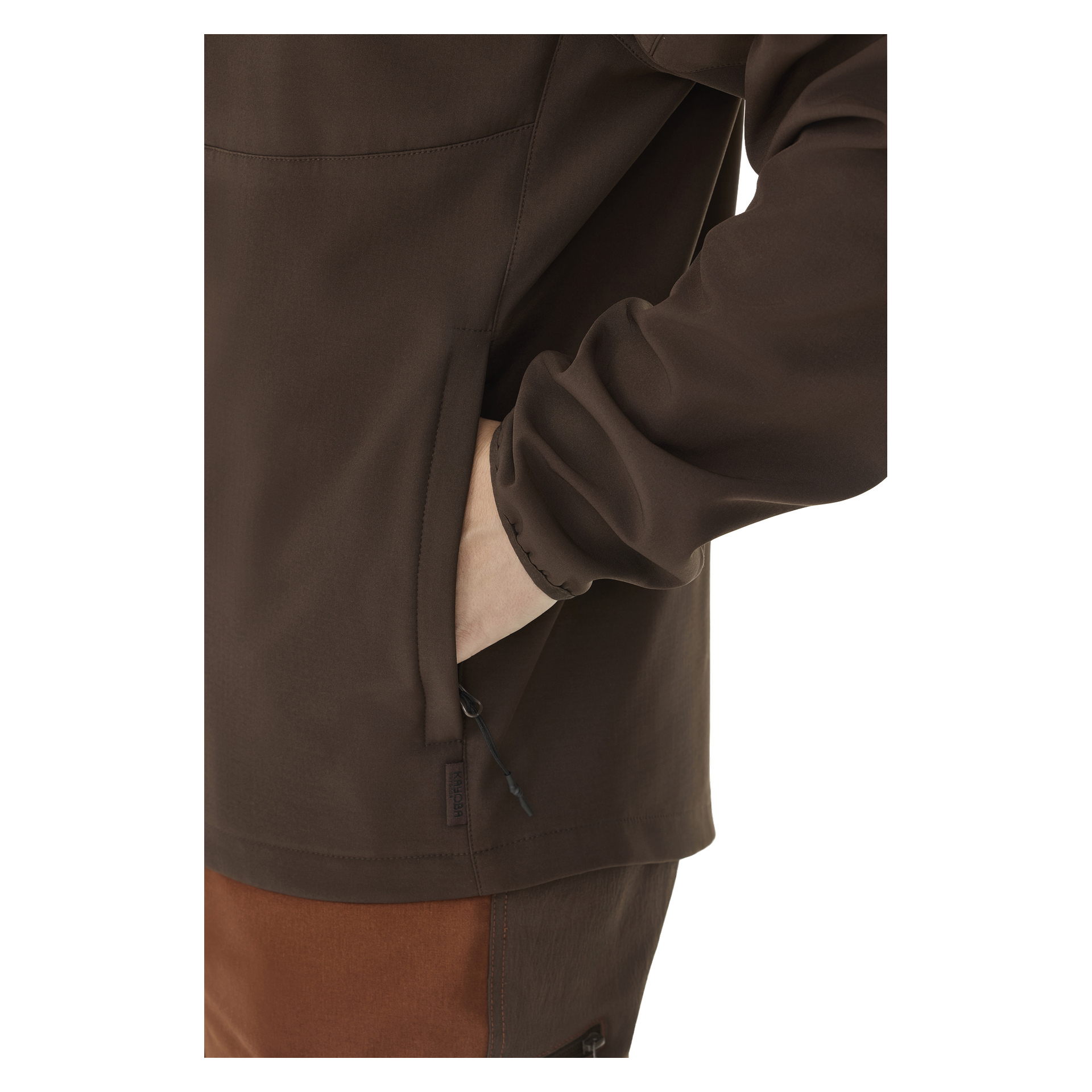 Man präsentiert die Kayoba Outdoor Women's Softshell-Jacke Hede mit Fleecefutter in dunkelbraunem Farbe, wobei die linke Hand teilweise in eine der Seitentaschen mit Reißverschluss gesteckt ist.