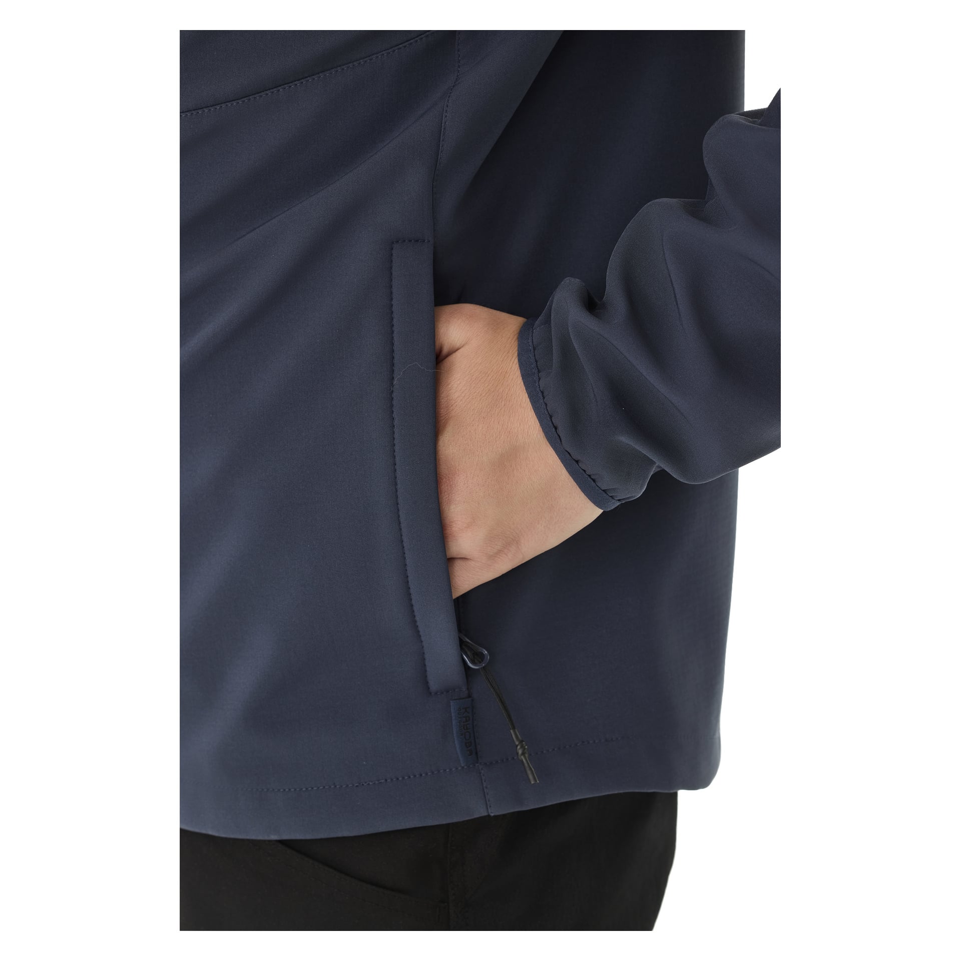 Henkilö nähdään tummansinisessä Kayoba Outdoor Women's -fleecevuoratussa pehmeäkuorisessa takissa Hede, oikea käsi takin taskussa. Näytetään vain käsi, osa hihasta ja takin alaosa.