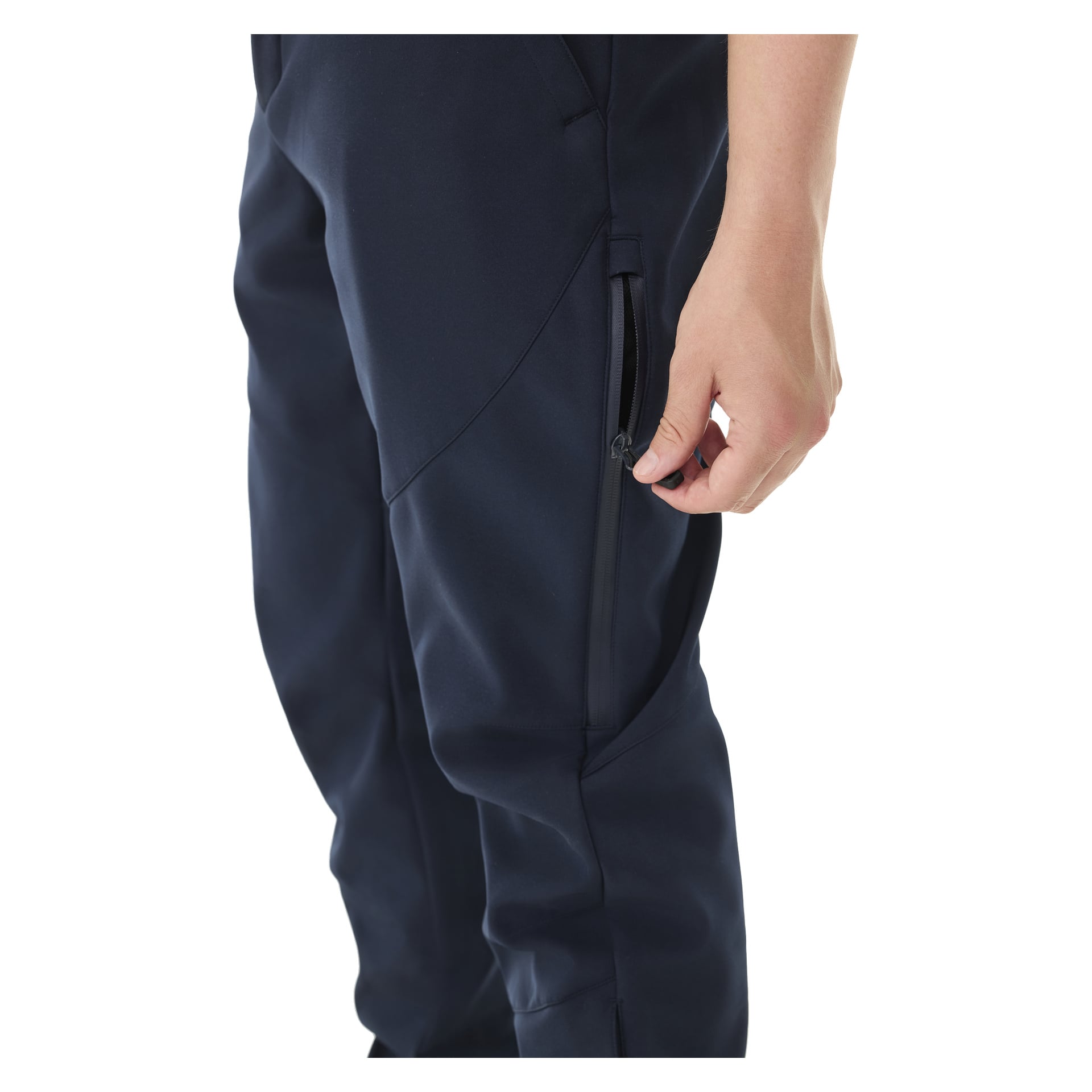 Henkilö näkyy vyötäröstä alaspäin, pukeutuneena tummansinisiin Kayoba Outdoor Men's -viirilliset softshell-housut. Toinen käsi puristaa vetoketjun vetää vetoketjua sivutaskussa.